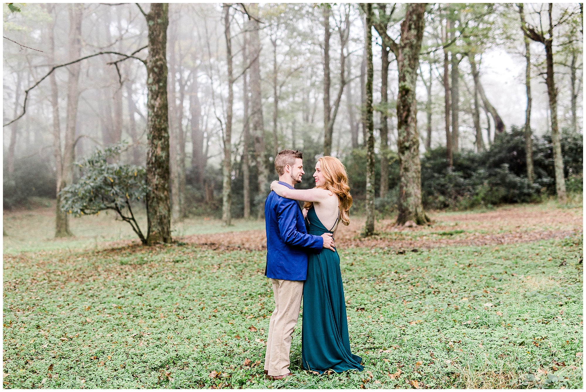 couple poses in front of trees with fog rolling in during foggy mountain engagement session