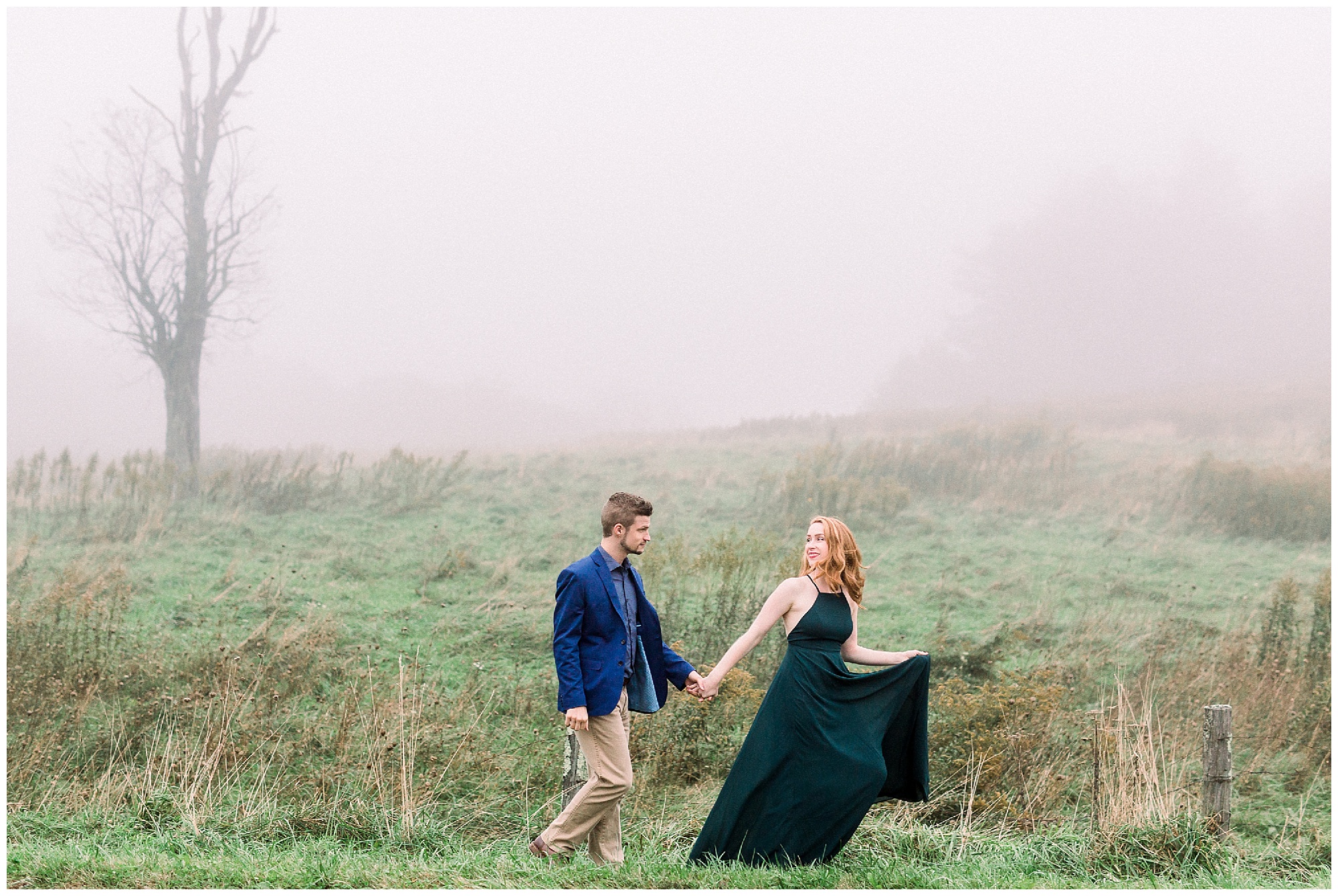 bride leads groom along field in emerald green gown during foggy mountain engagement session