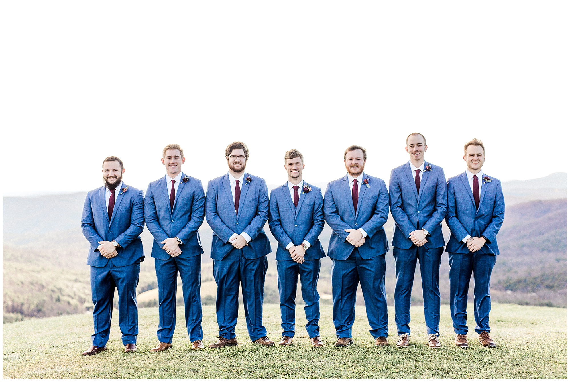 groom poses with groomsmen in navy suits on mountaintop in Asheville NC 