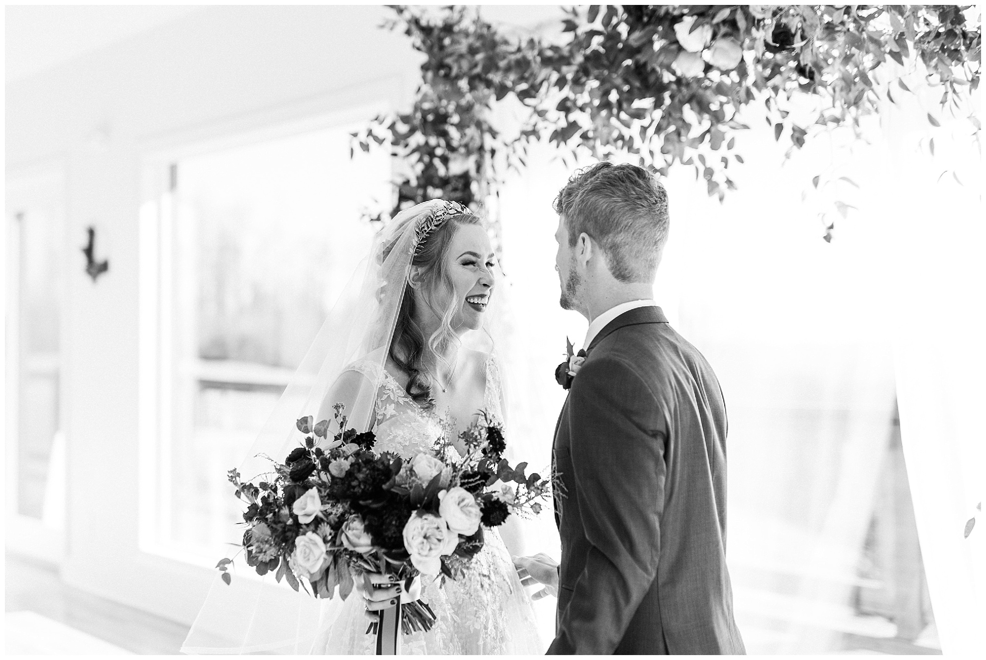 bride and groom laugh together during first look by floral arch at Sky Retreat 