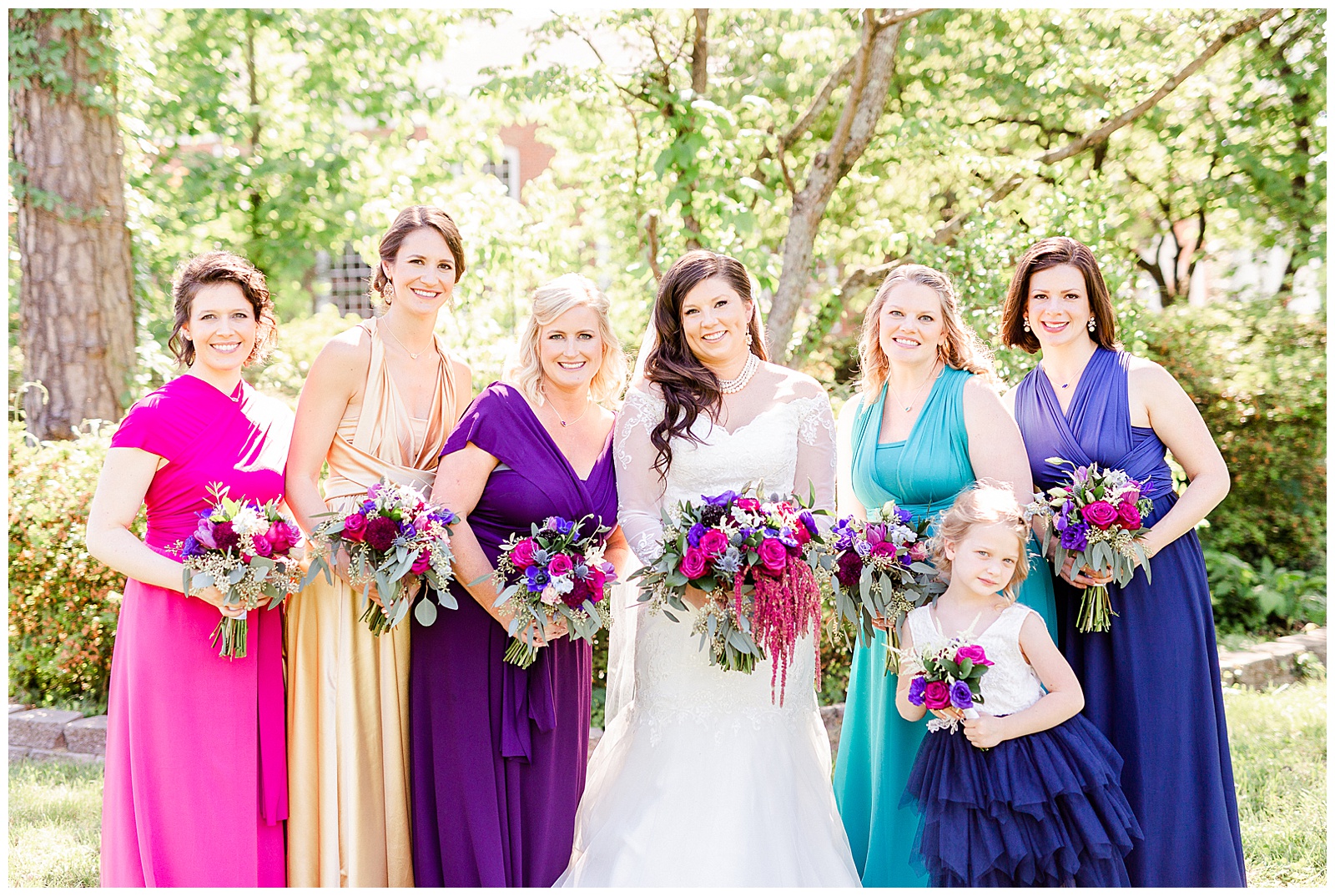 💍 bridal shot wedding veil + bride and bright colorful bridesmaids group photo wedding portrait in lace wedding dress with rhinestone belt rhinestone barrette in hair down with pearls and pink, purple, blue, and gold bridesmaid dresses 💍 Bright Colorful Summer City Wedding in Charlotte, NC with Taryn and Ryan | Kevyn Dixon Photography