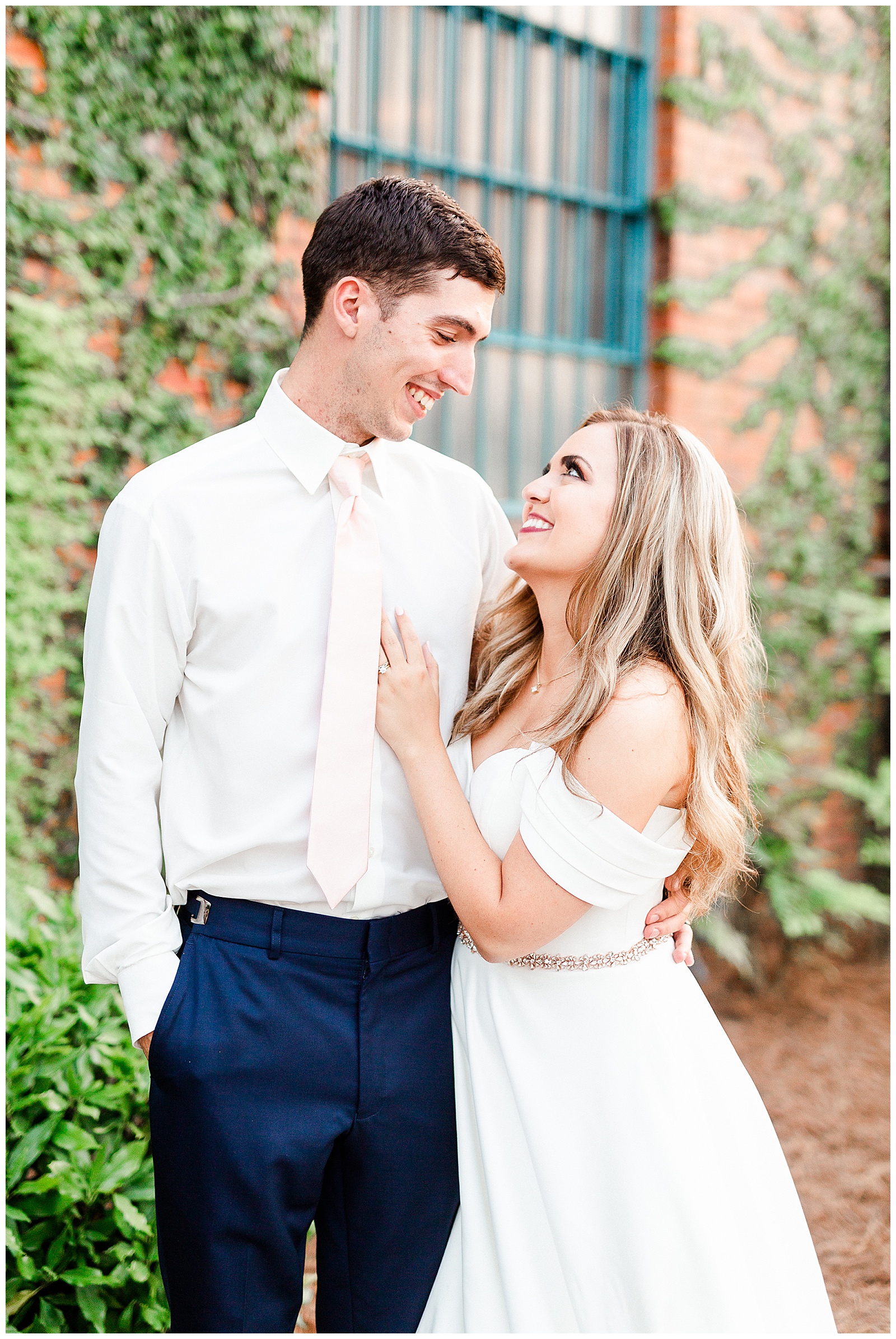Stunning Modern Bride and Groom with off shoulder wedding dress and blue suit in outdoor portraits in front of vine-covered brick building from Summer Wedding in Charlotte, NC | Check out the full wedding at KevynDixonPhoto.com