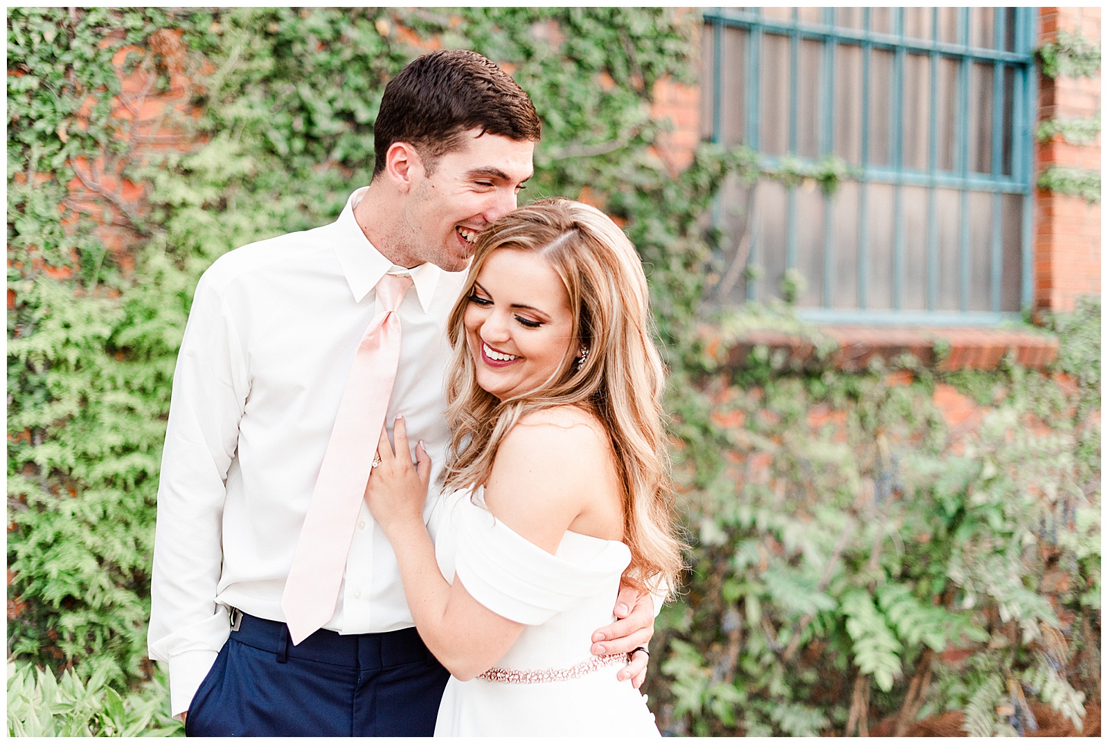 Stunning Modern Bride and Groom with off shoulder wedding dress and blue suit in outdoor portraits in front of vine-covered brick building from Summer Wedding in Charlotte, NC | Check out the full wedding at KevynDixonPhoto.com