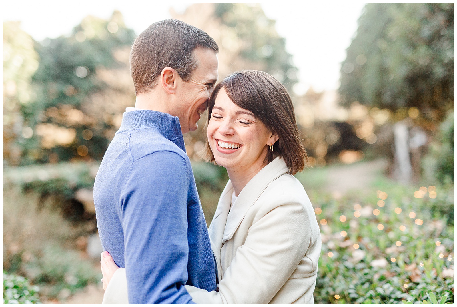 Sweet Couple Laughing in Park at Outdoor Winter Engagement Session in NC - white coat, short brown hair bride outfit ideas