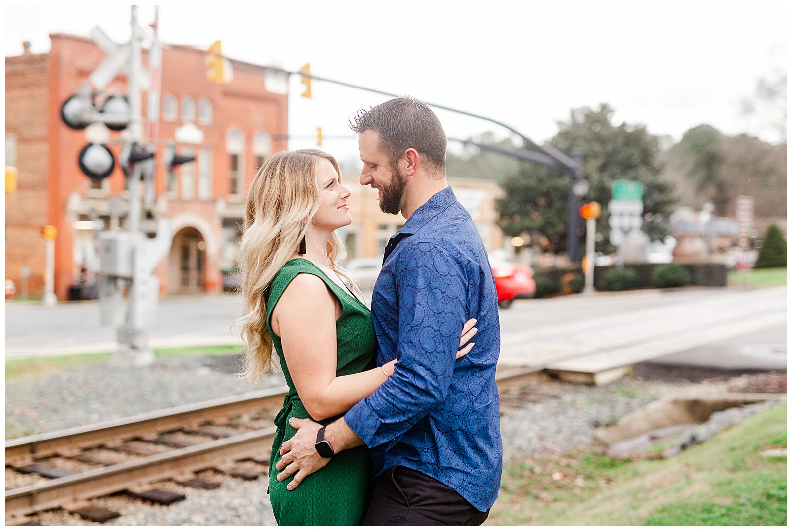 Adorable couple near old train tracks in downtown Waxhaw, NC Engagement Session with Green Dress Outfit Ideas