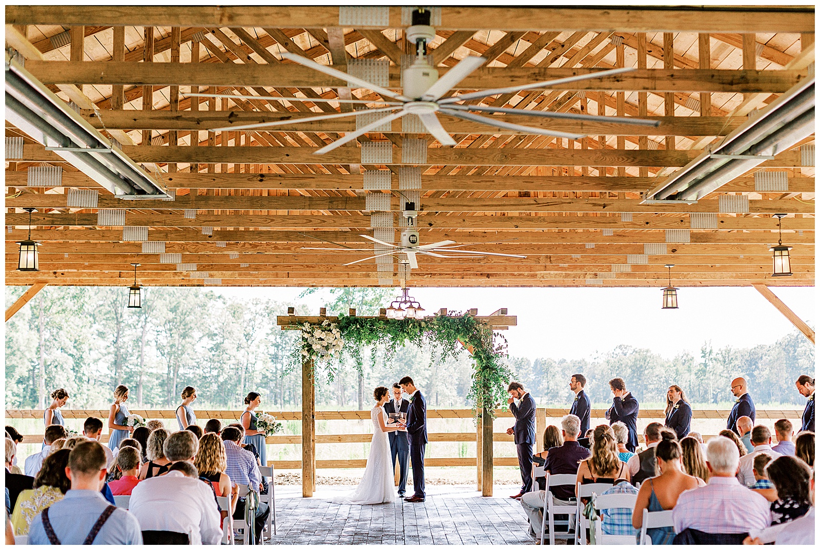 huge open barn summer wedding venue ceremony time under simple greenery arch called the farmstead in north carolina