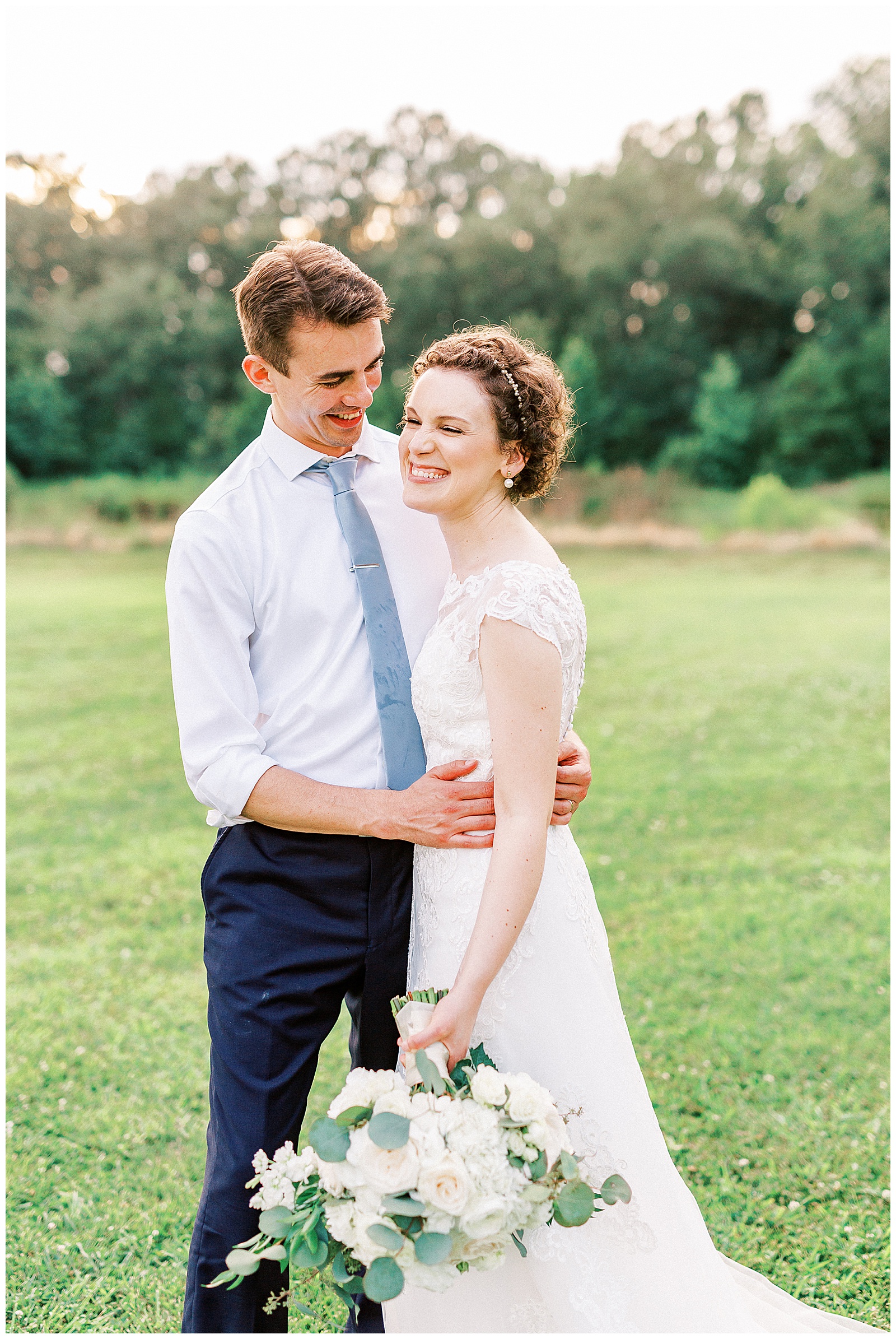 summer sunset in field wedding day bride groom portraits with curly short haired bride with lace wedding dress and navy blue suit groom
