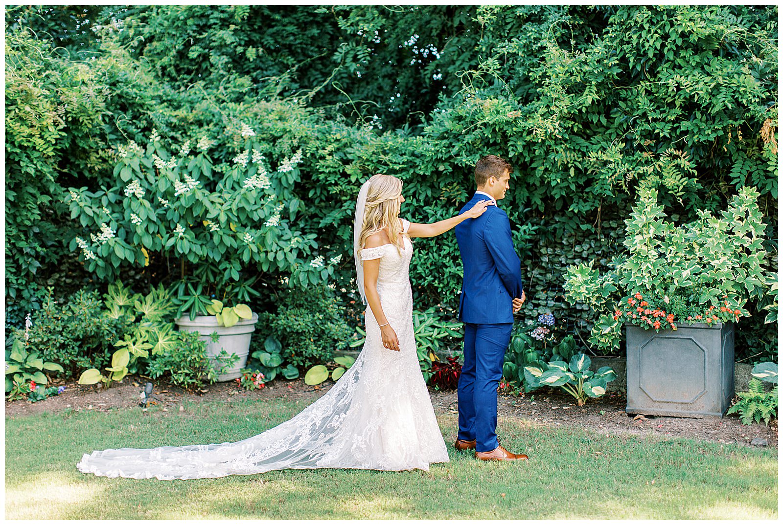 royal blue suited groom and blonde haired bride emotional first look outdoor in garden