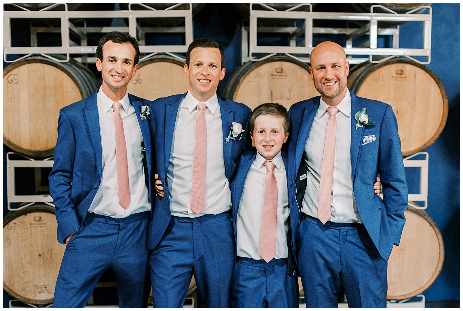 indoor summer wedding groomsmen portrait in navy blue suits and pink tie
