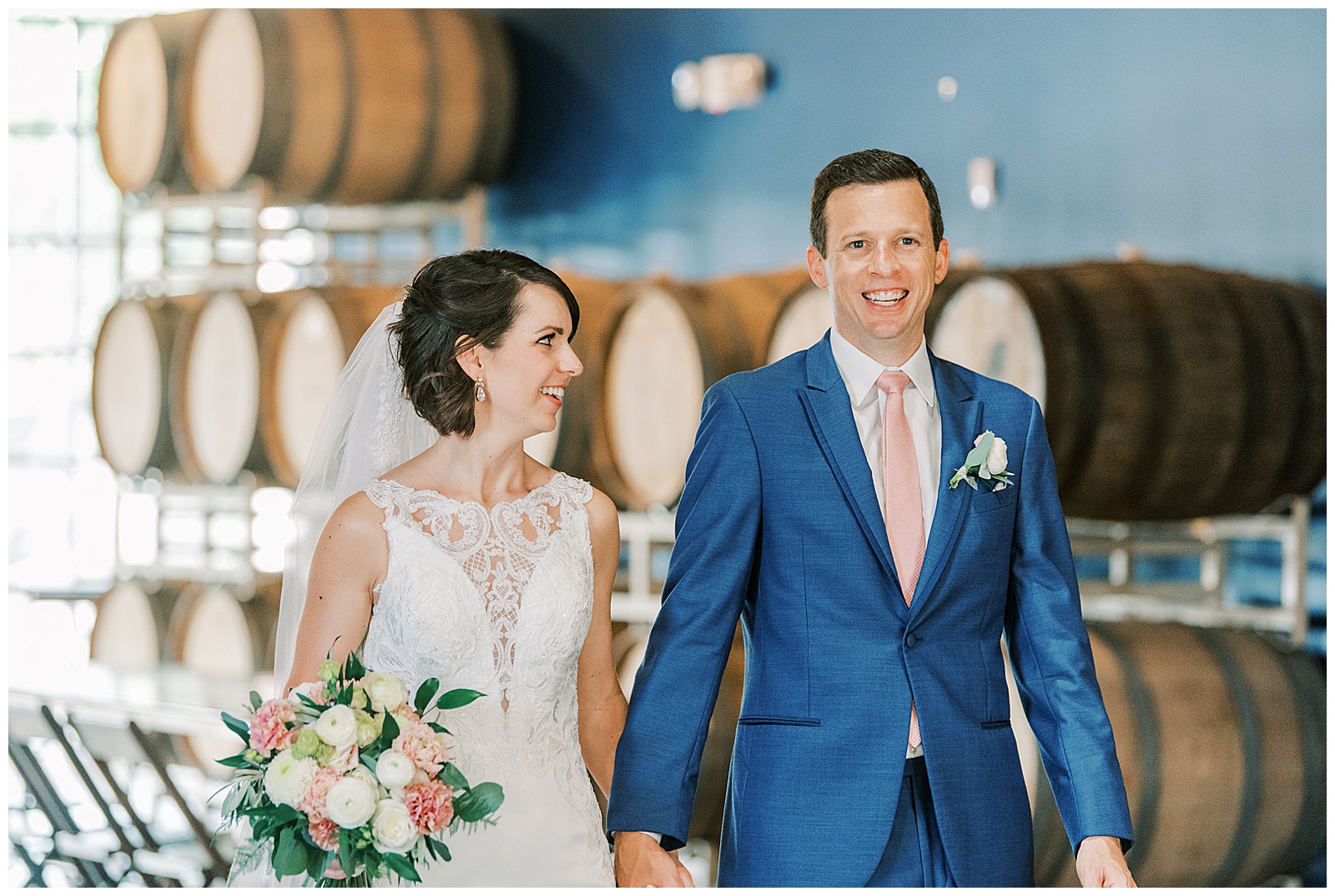 indoor summer bride groom portraits of short brown haired bride in lace dress with long train and navy blue suited groom