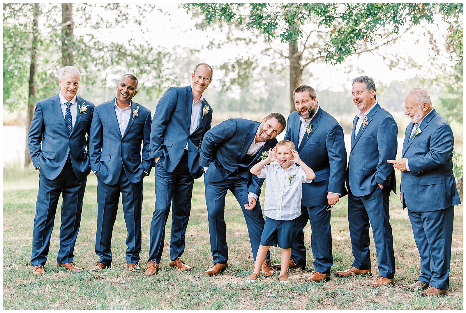 groomsmen group portrait in navy blue suits with silly son of groom