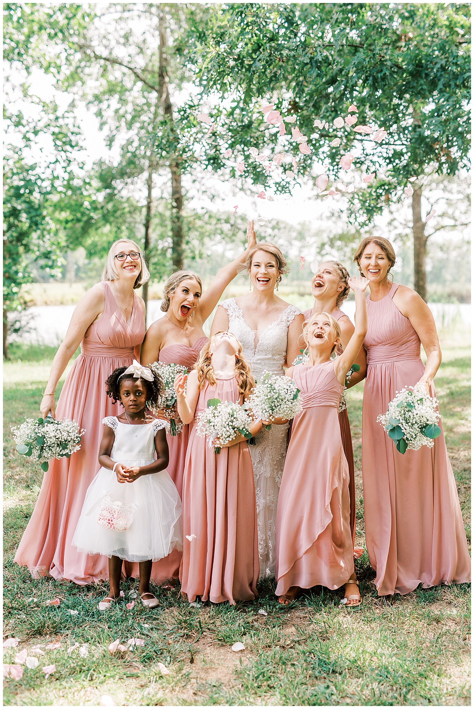tossing petals in the air for sweet pink bride tribe portraits for outdoor summer wedding