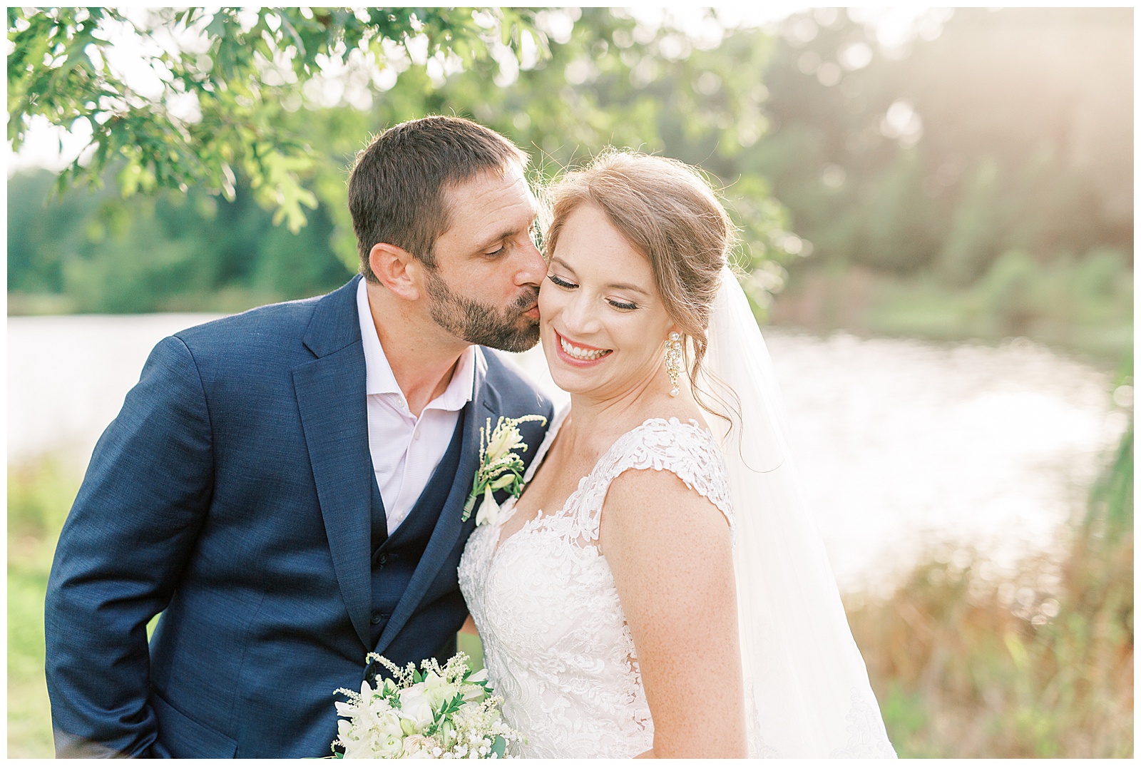 stunning cathedral veil blond haired bride and navy blue suit groom in outdoor summer wedding portraits