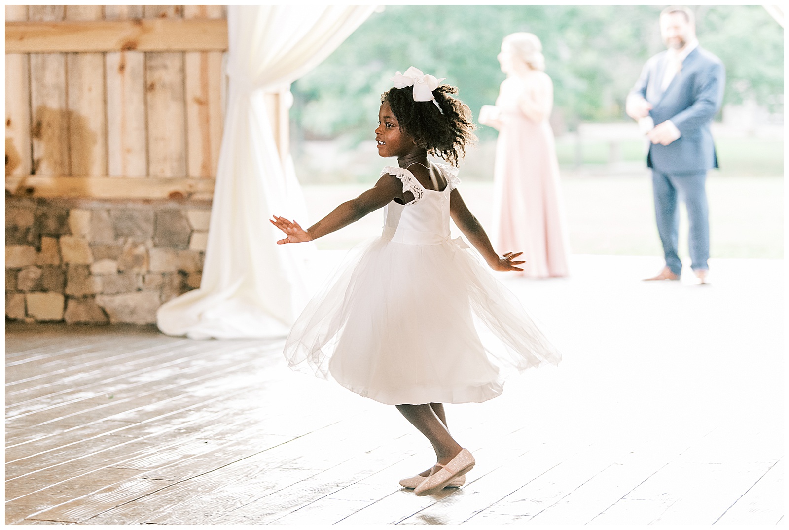 adorable flower girl in white dress twirls in wedding reception entry