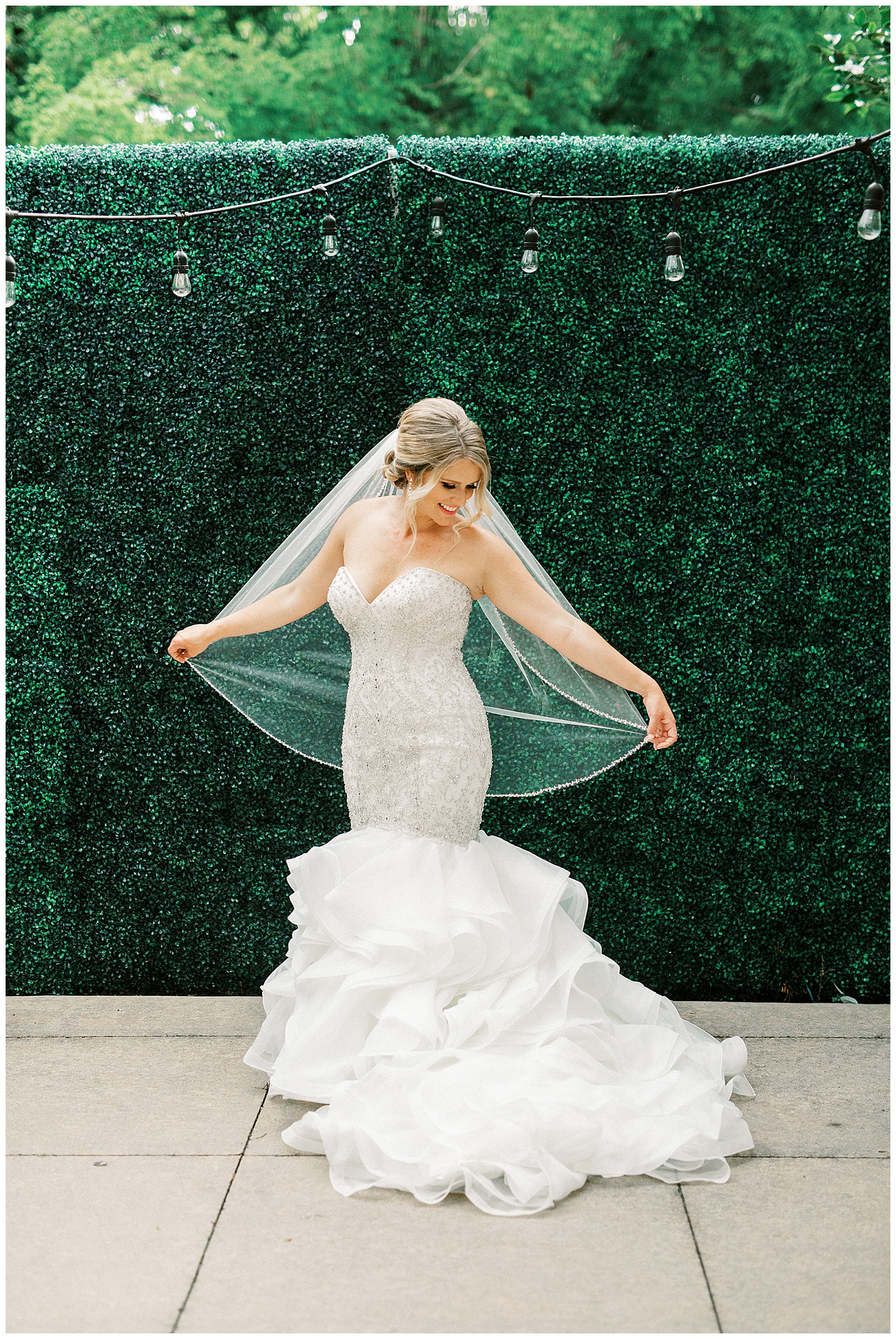 gorgeous light and airy outdoor bridal portraits with blonde haired bride in front of greenery wall