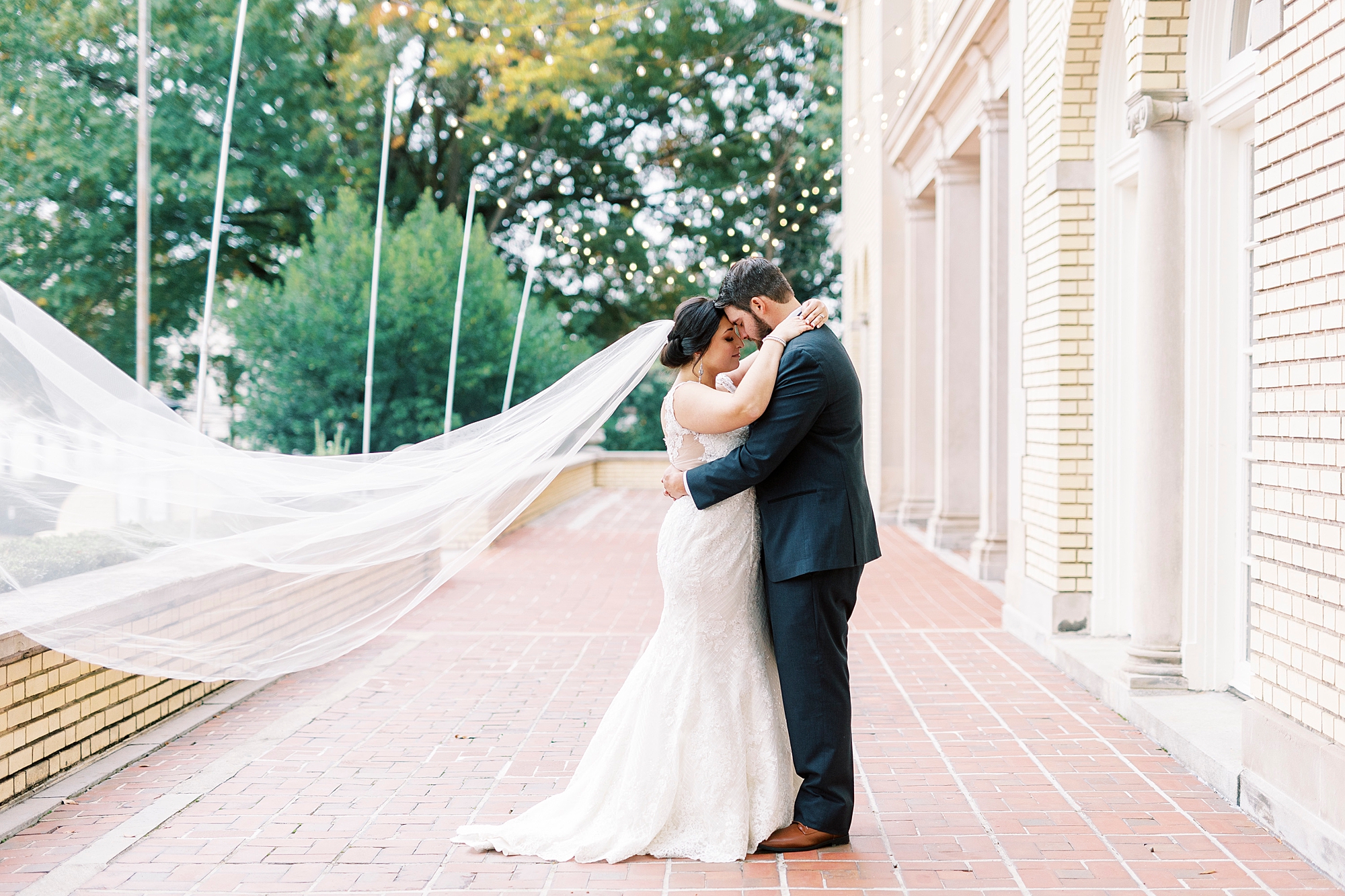 bride and groom hug with bride's veil floating behind them next to Separk Mansion