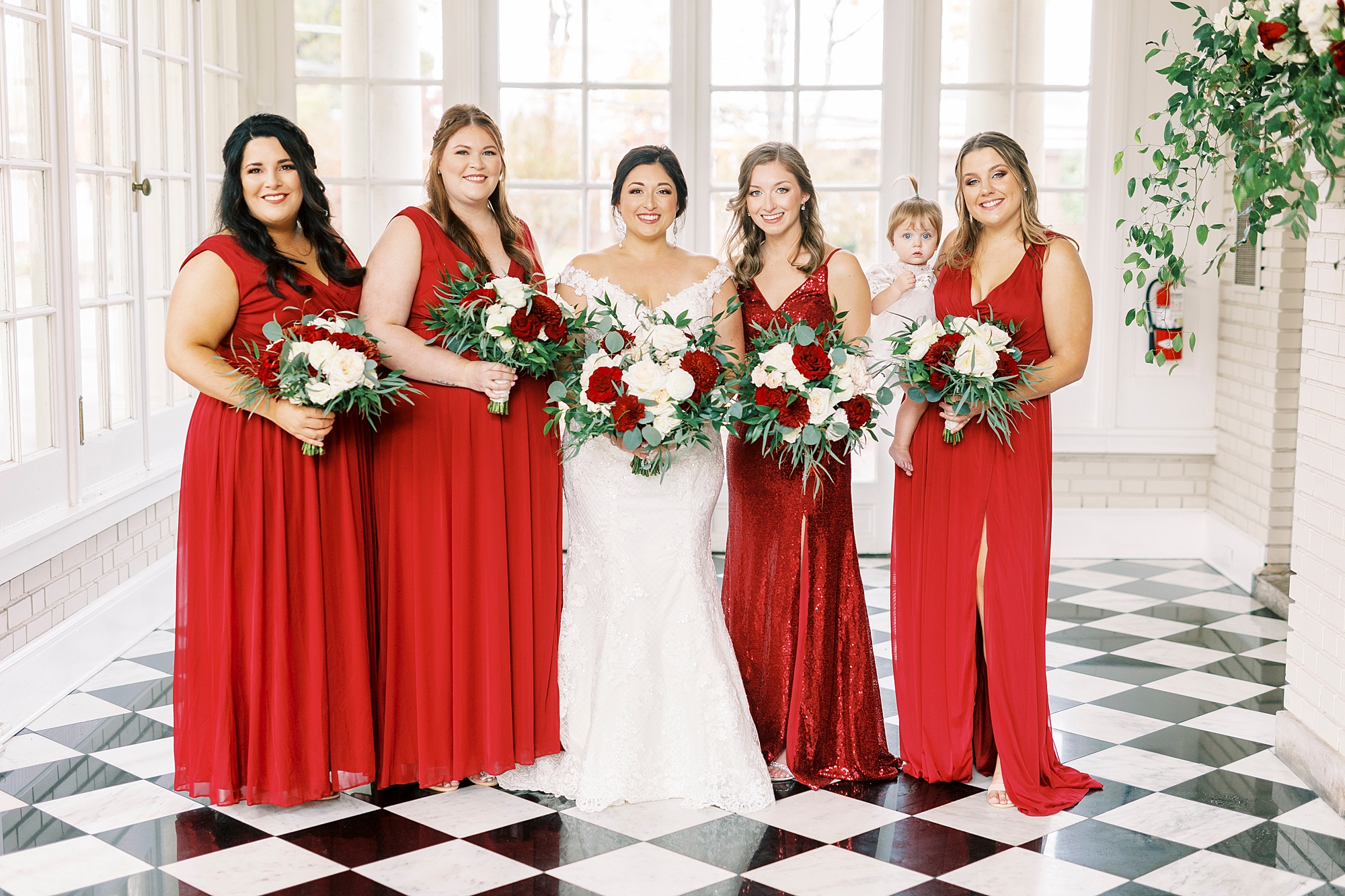 bride poses with bridesmaids in red gowns before fall wedding at Separk Mansion