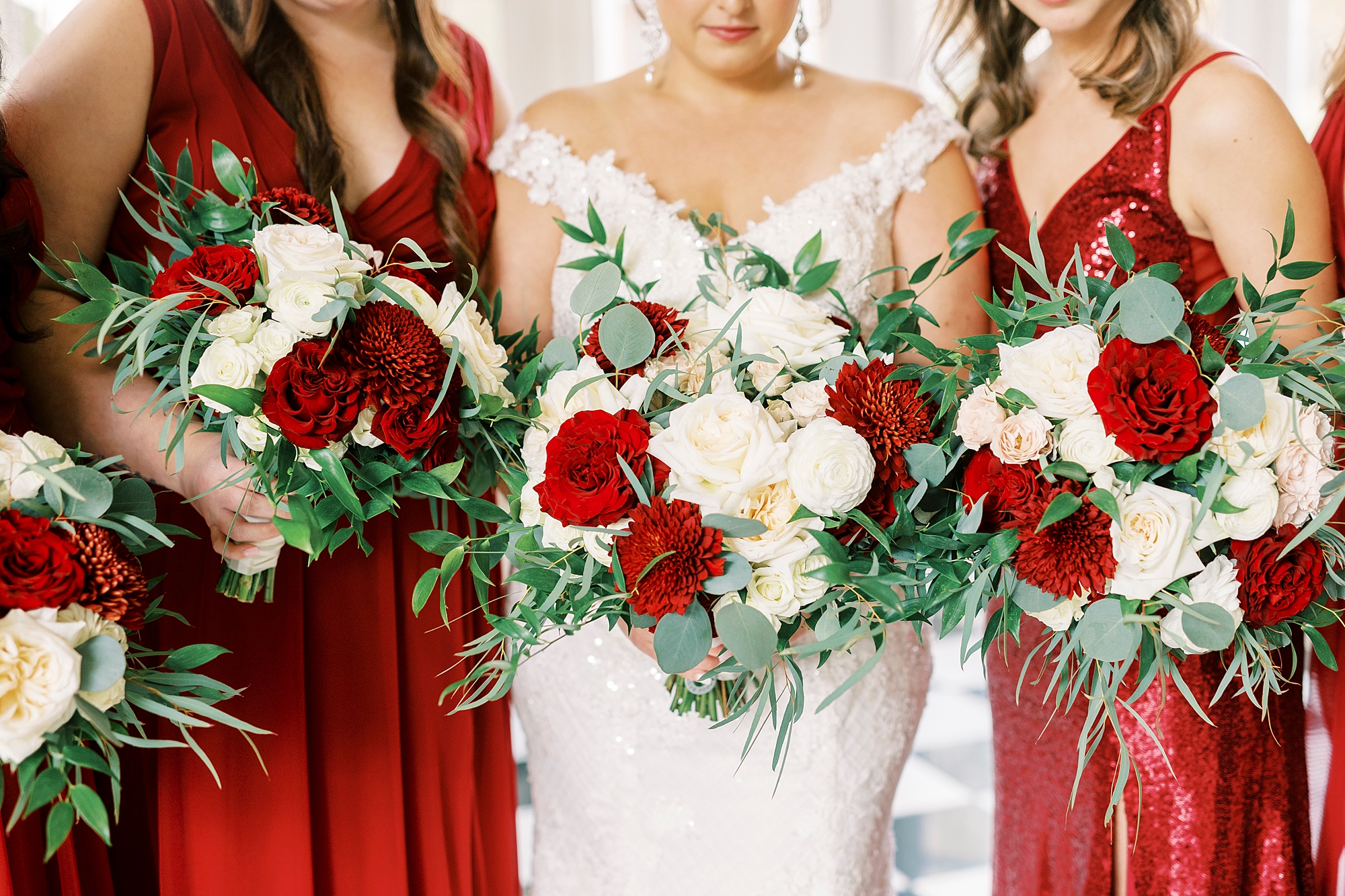 bride and bridesmaids hold red and pink rose bouquets for fall wedding at Separk Mansion