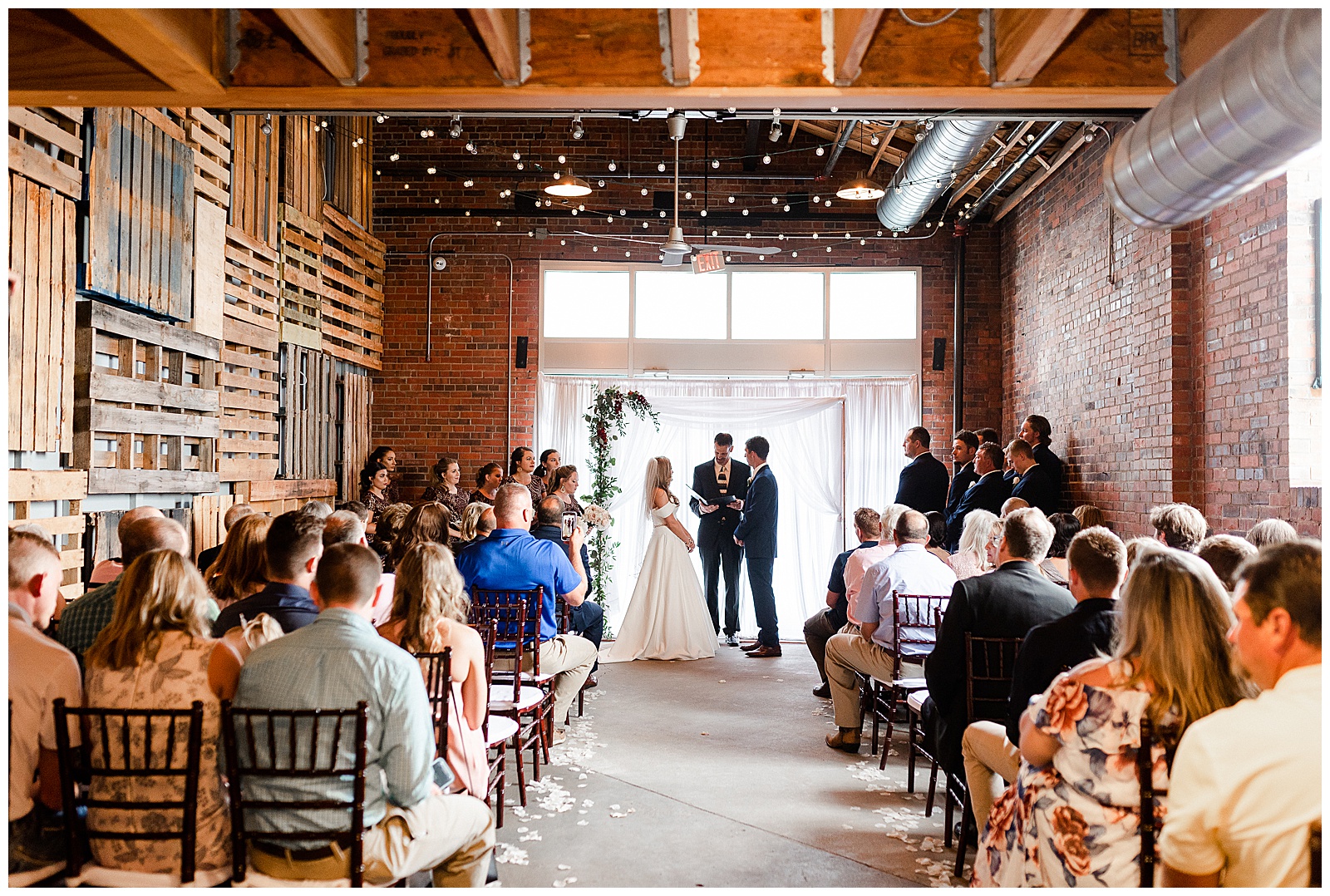Bride and Groom during summer wedding ceremony in stunning indoor venue with fairy lights in Charlotte, NC | Check out the full wedding at KevynDixonPhoto.com