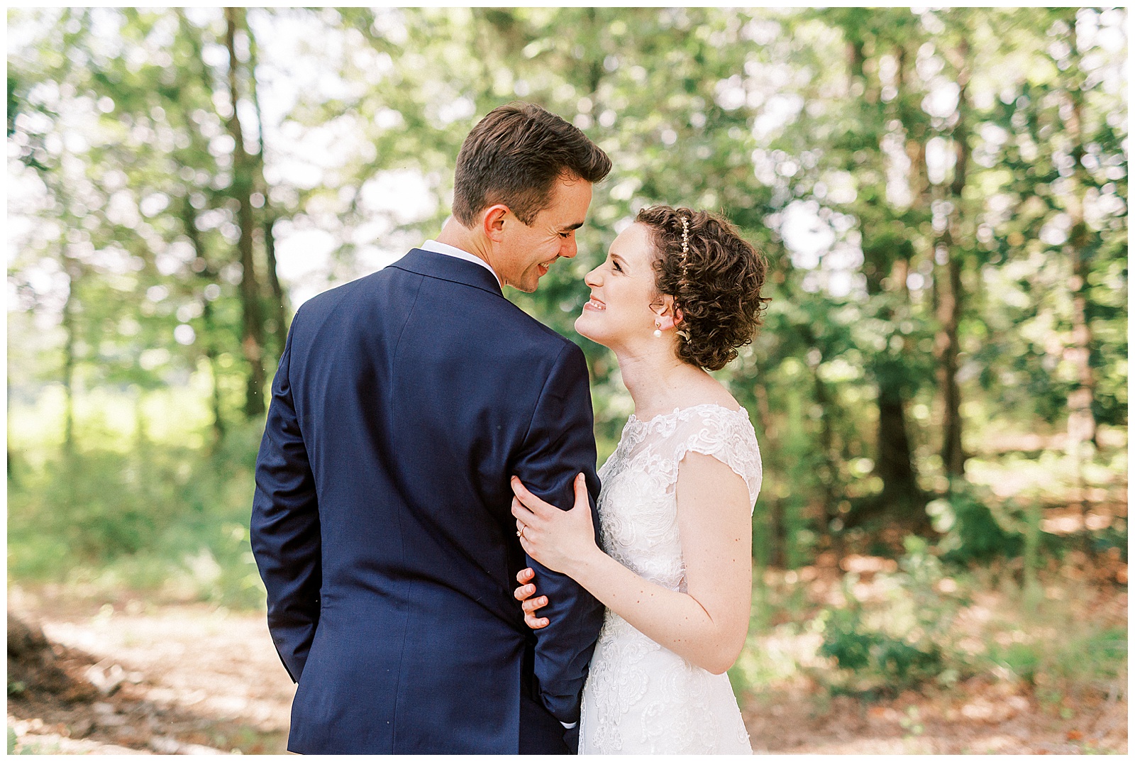 outside bride groom wedding day portraits curly short haired bride with lace wedding dress and navy blue suit groom