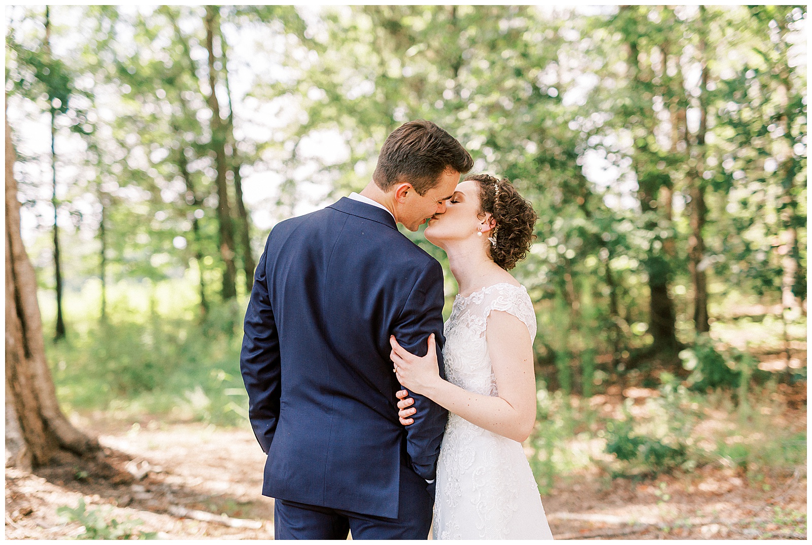 outside bride groom wedding day portraits curly short haired bride with lace wedding dress and navy blue suit groom