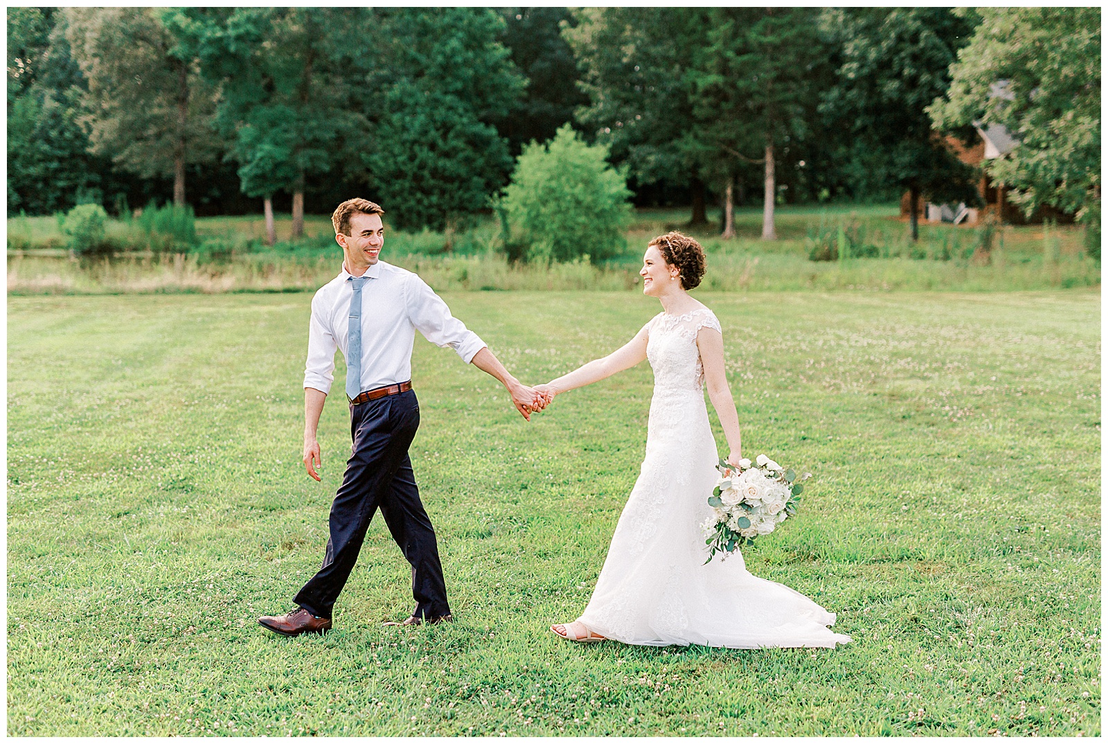 summer sunset in field wedding day bride groom portraits with curly short haired bride with lace wedding dress and navy blue suit groom