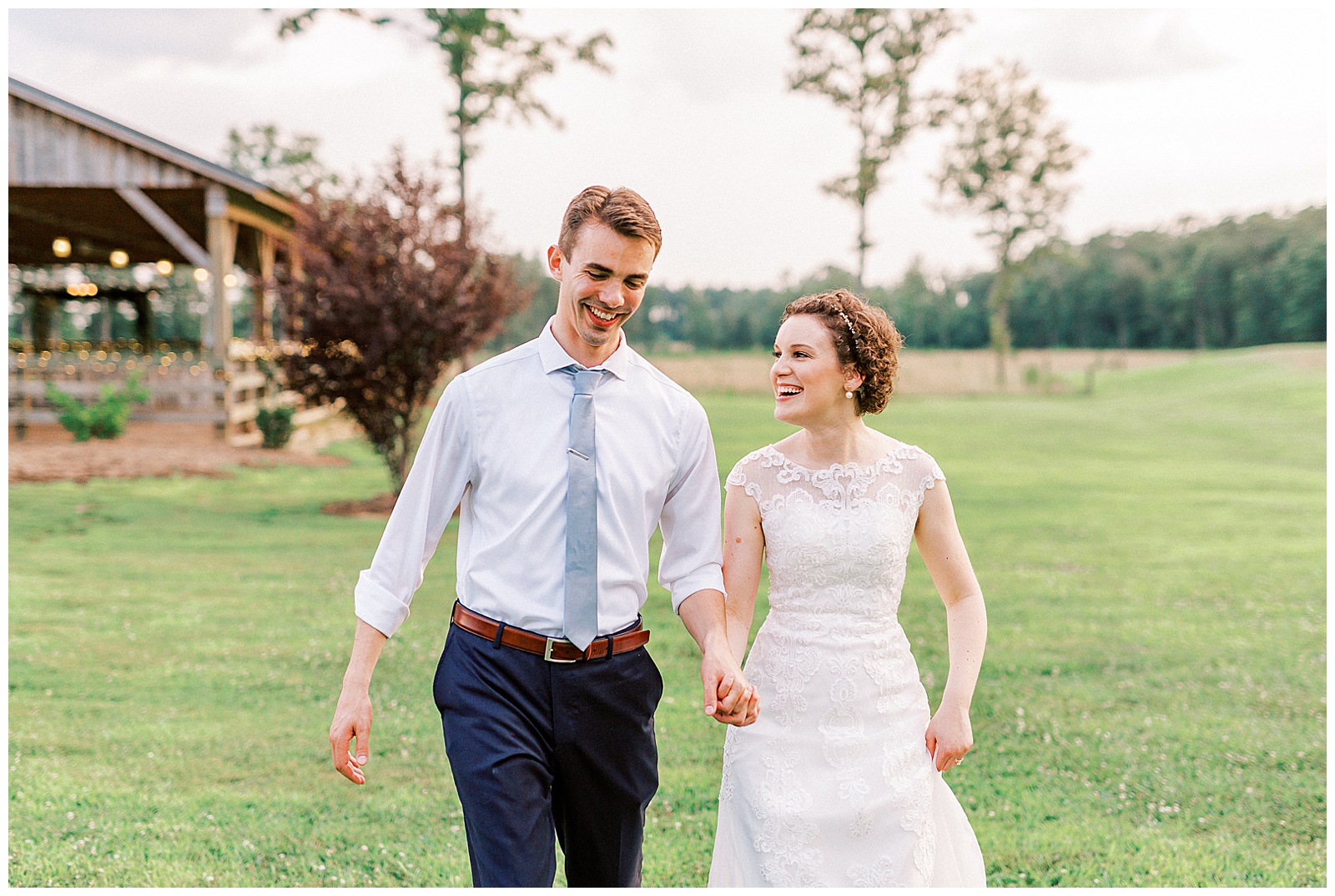 summer sunset in field wedding day bride groom portraits with curly short haired bride with lace wedding dress and navy blue suit groom