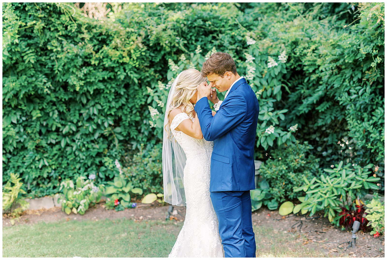 royal blue suited groom and blonde haired bride emotional first look outdoor in garden