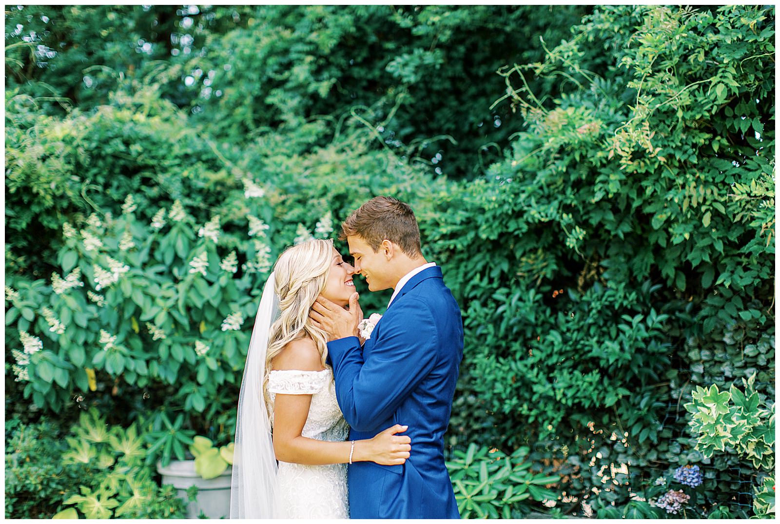 royal blue suited groom and blonde haired bride emotional first look outdoor in garden