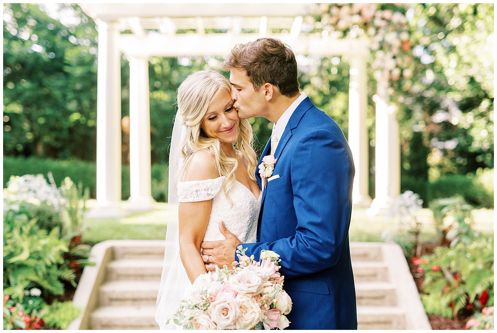 lace dress blond haired bride and dapper navy royal blue groom portraits outdoors under arch at separk mansion summer wedding