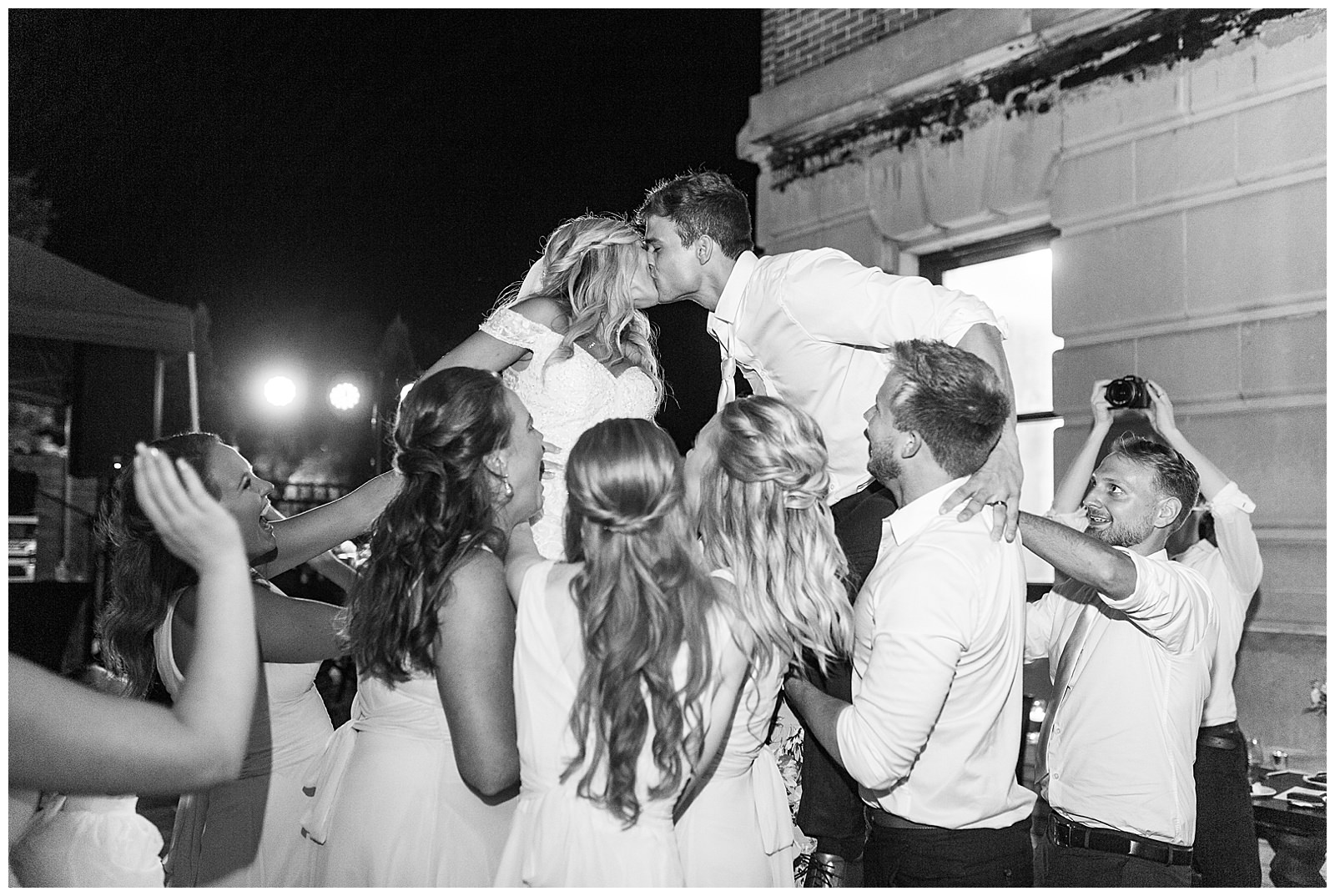 bride and groom kiss while crowd surfing at esquire hotel outdoor patio wedding reception
