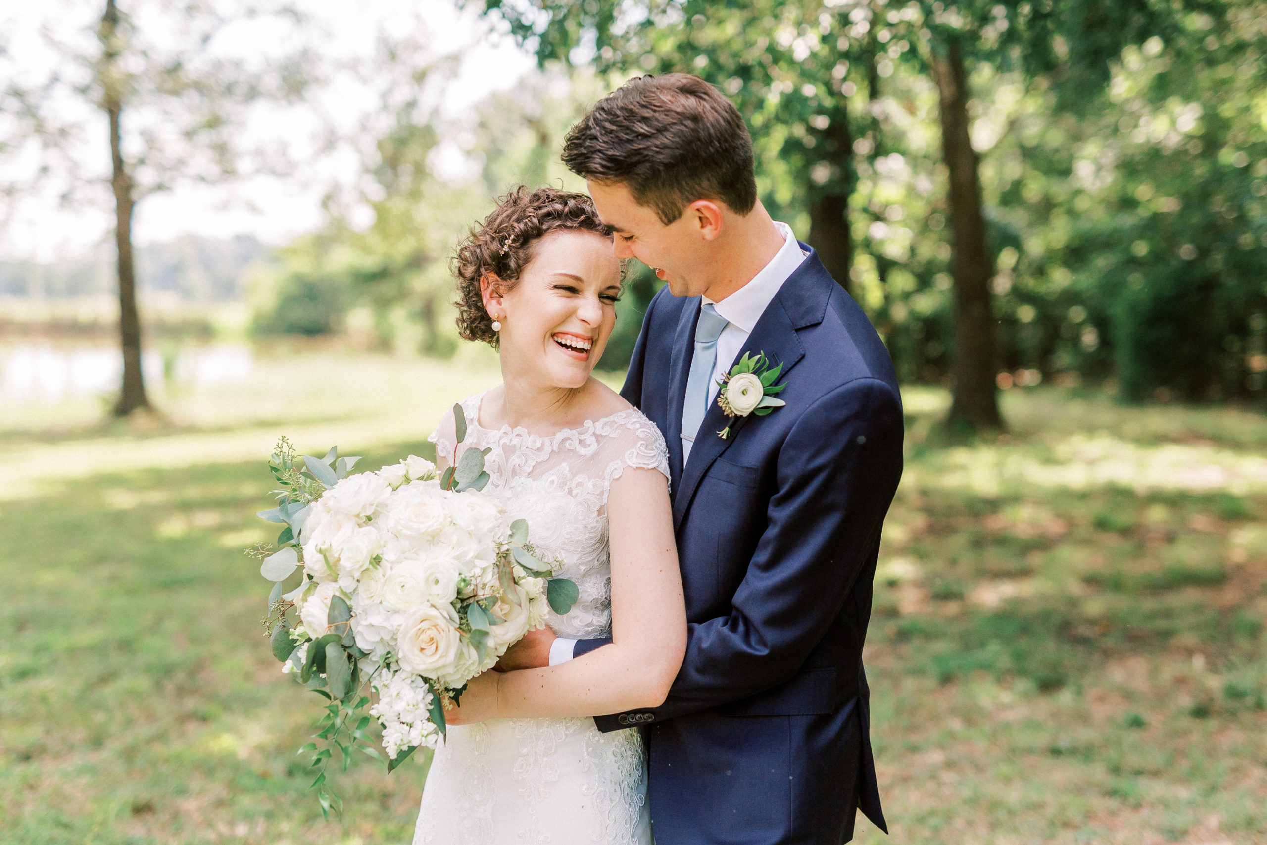 outside bride groom wedding day portraits curly short haired bride with lace wedding dress and navy blue suit groom