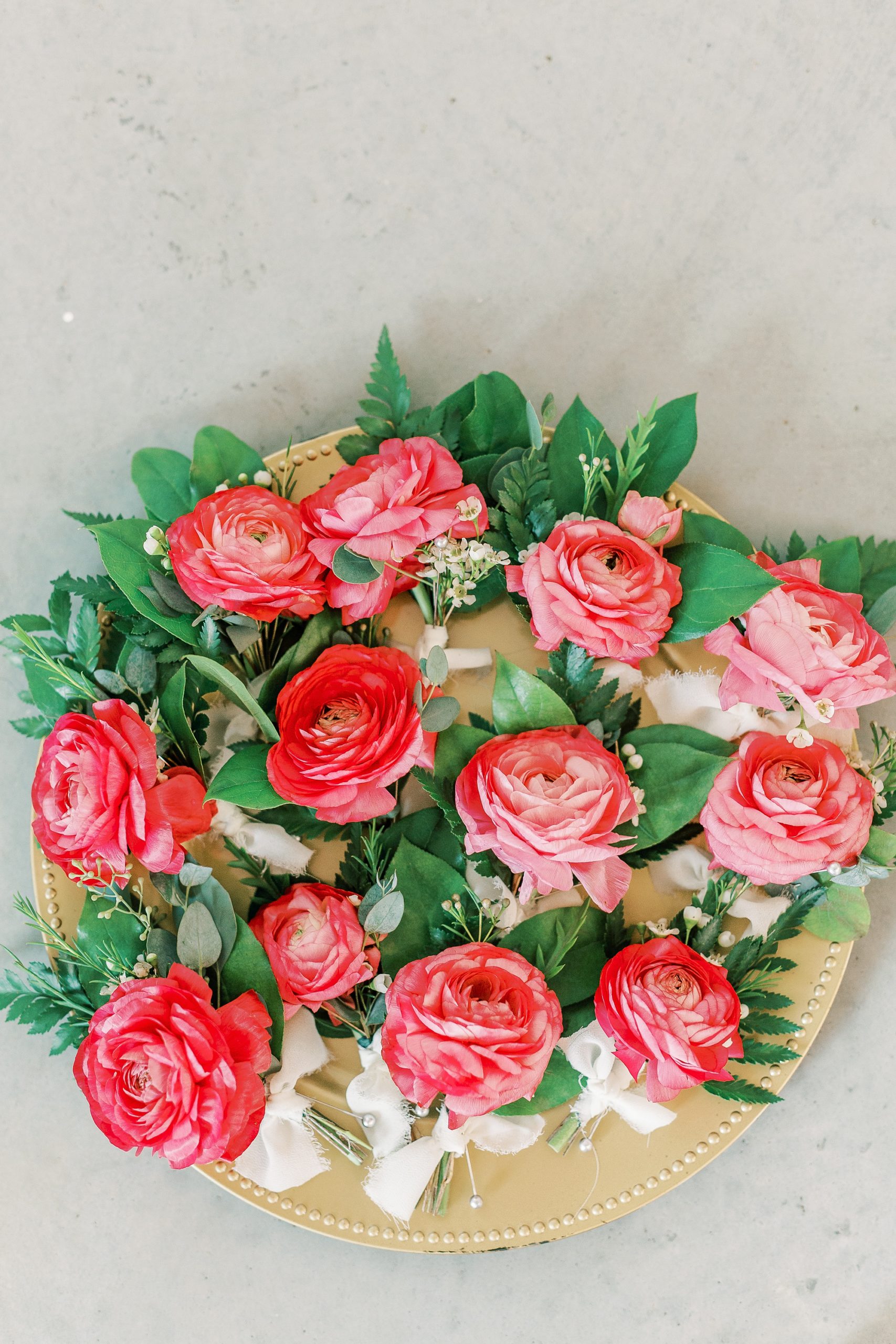 pink boutonnières rest on gold charger