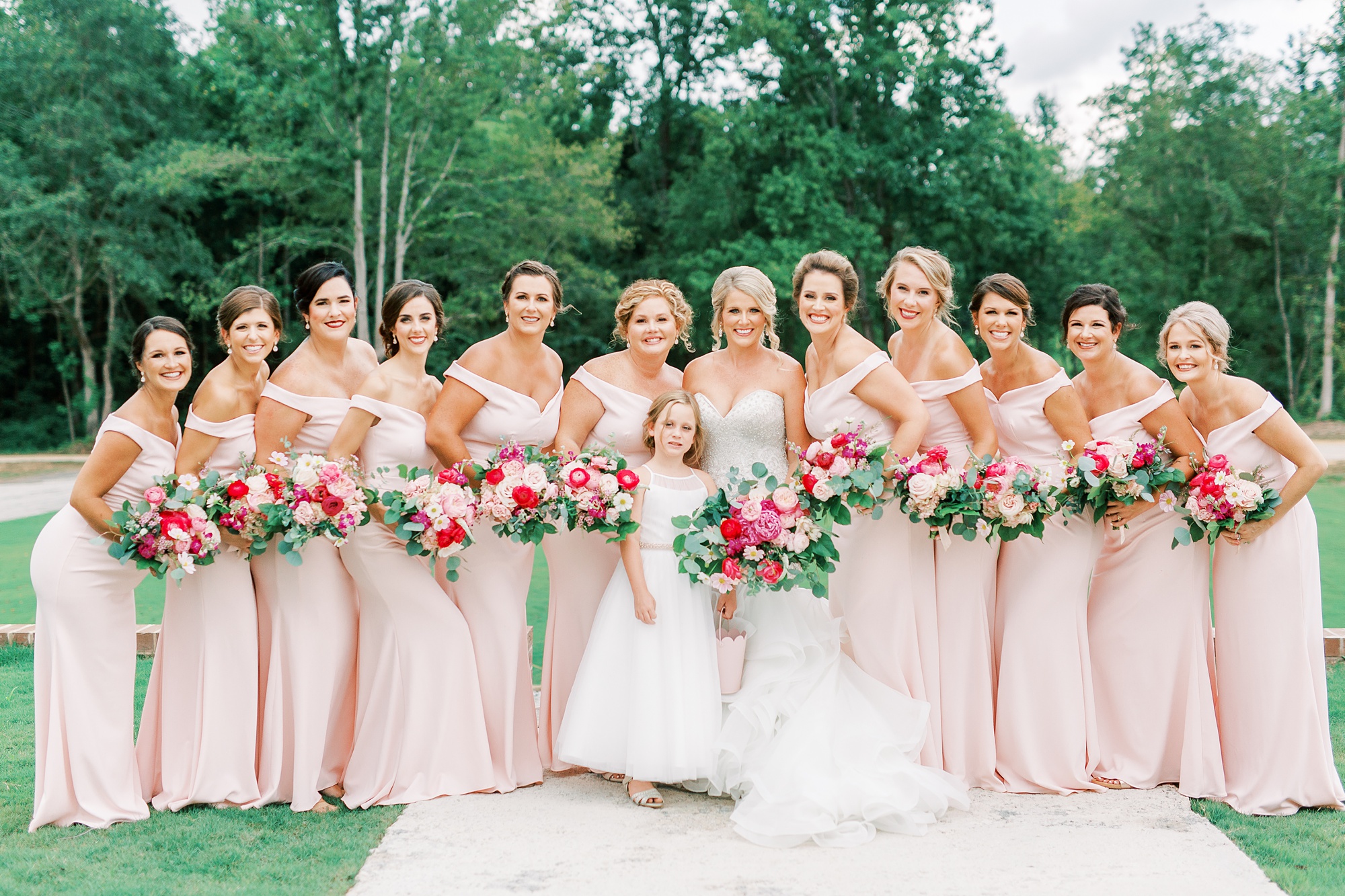 bride poses with bridesmaids in pale pink dresses