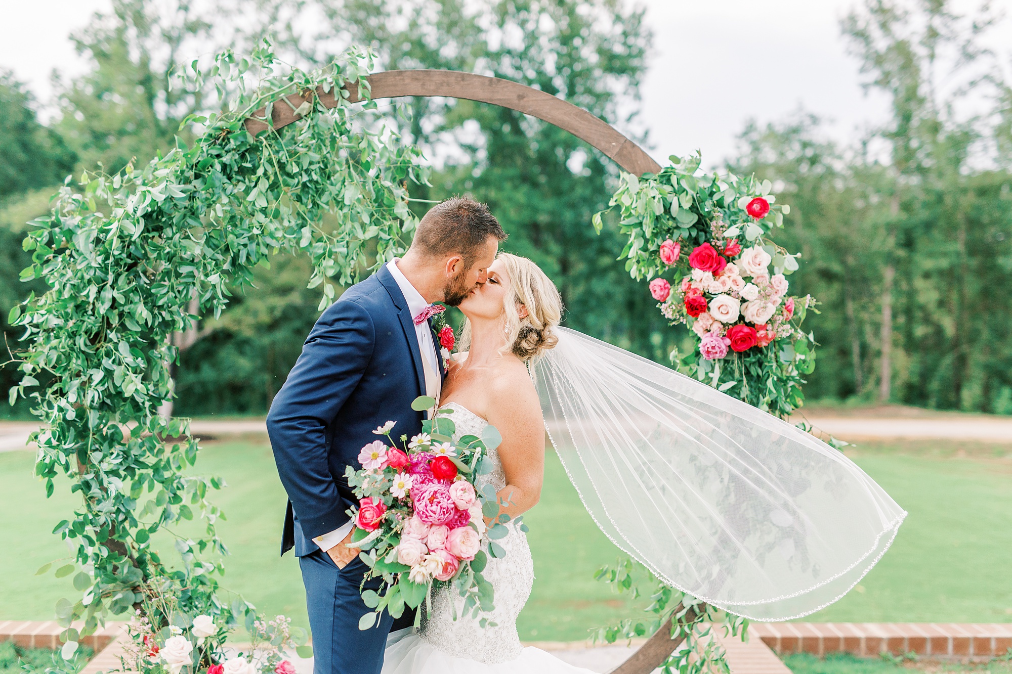 bride and groom kiss with veil floating in air