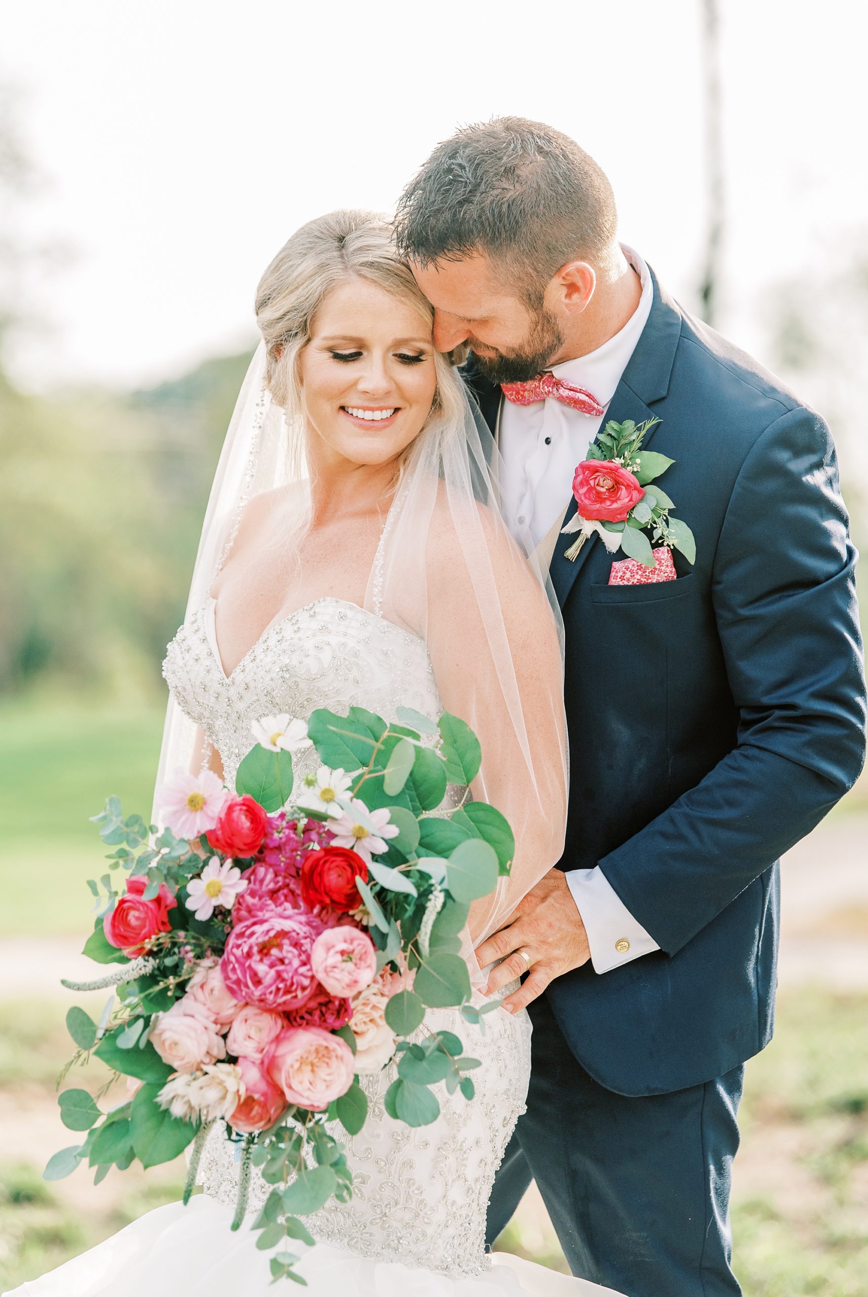 bride and groom stand together in front of sunset