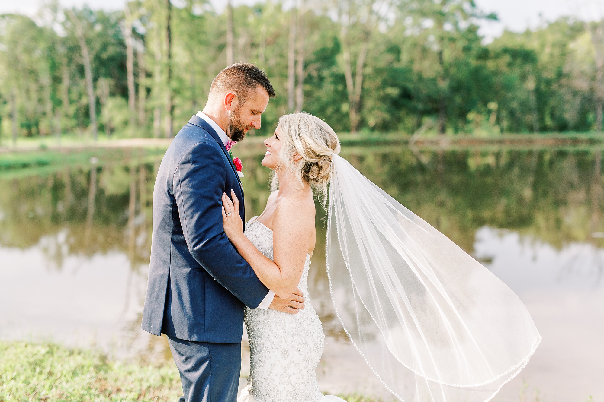 bride and groom smile together while veil floats in the air