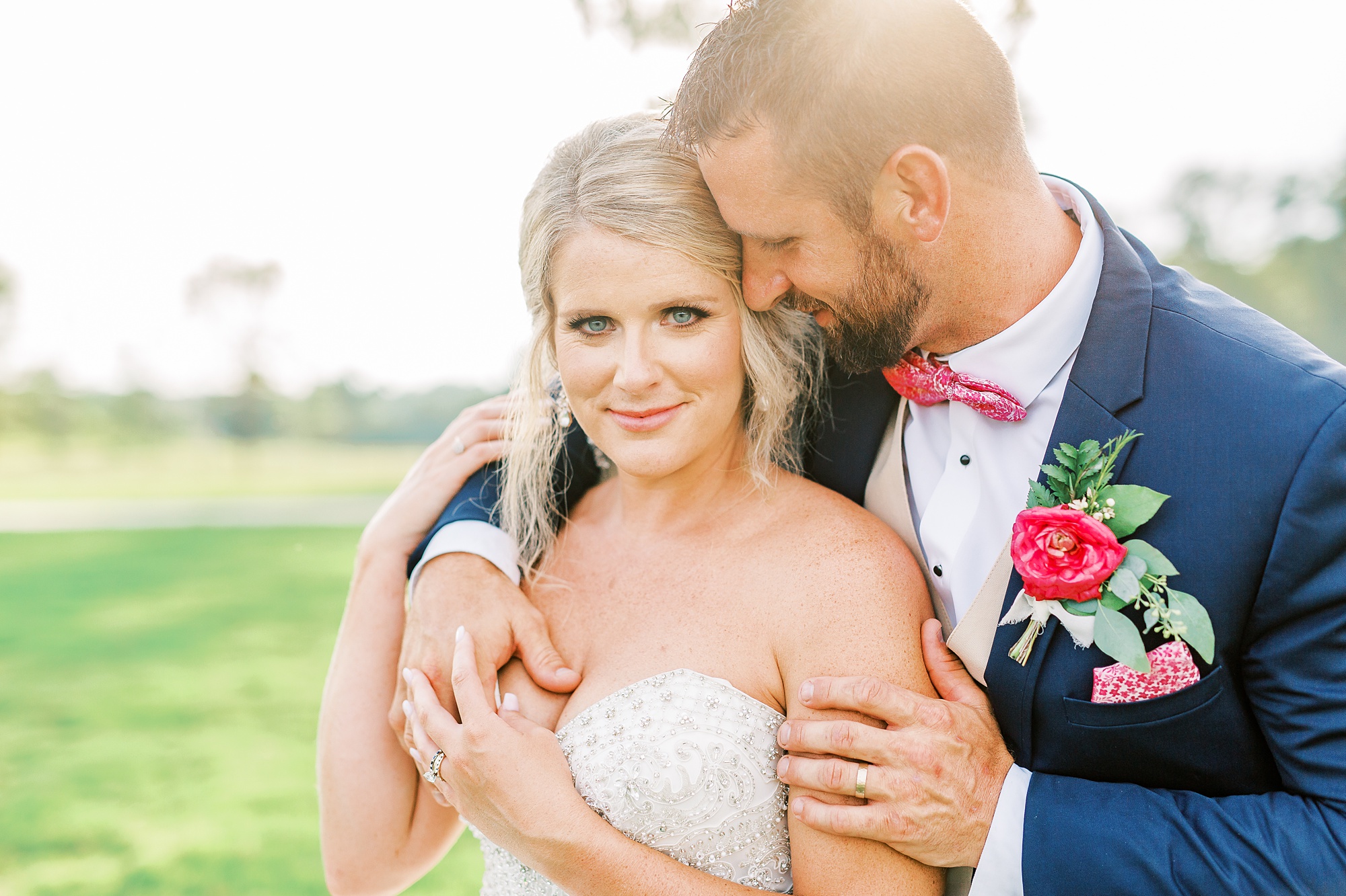 groom holds bride around shoulders while she stares into camera