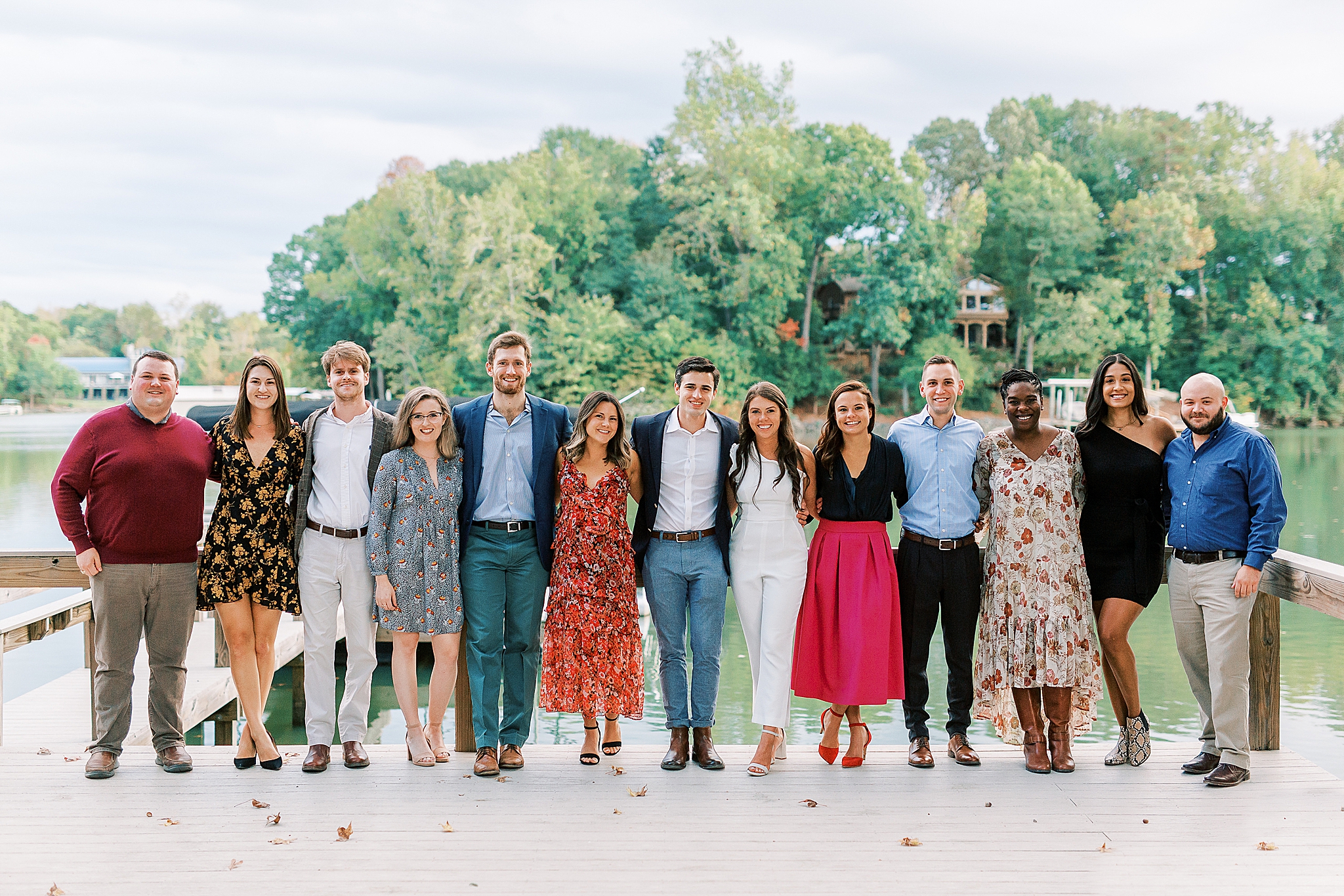 bride and groom pose with wedding party during welcome dinner at Lake Wylie
