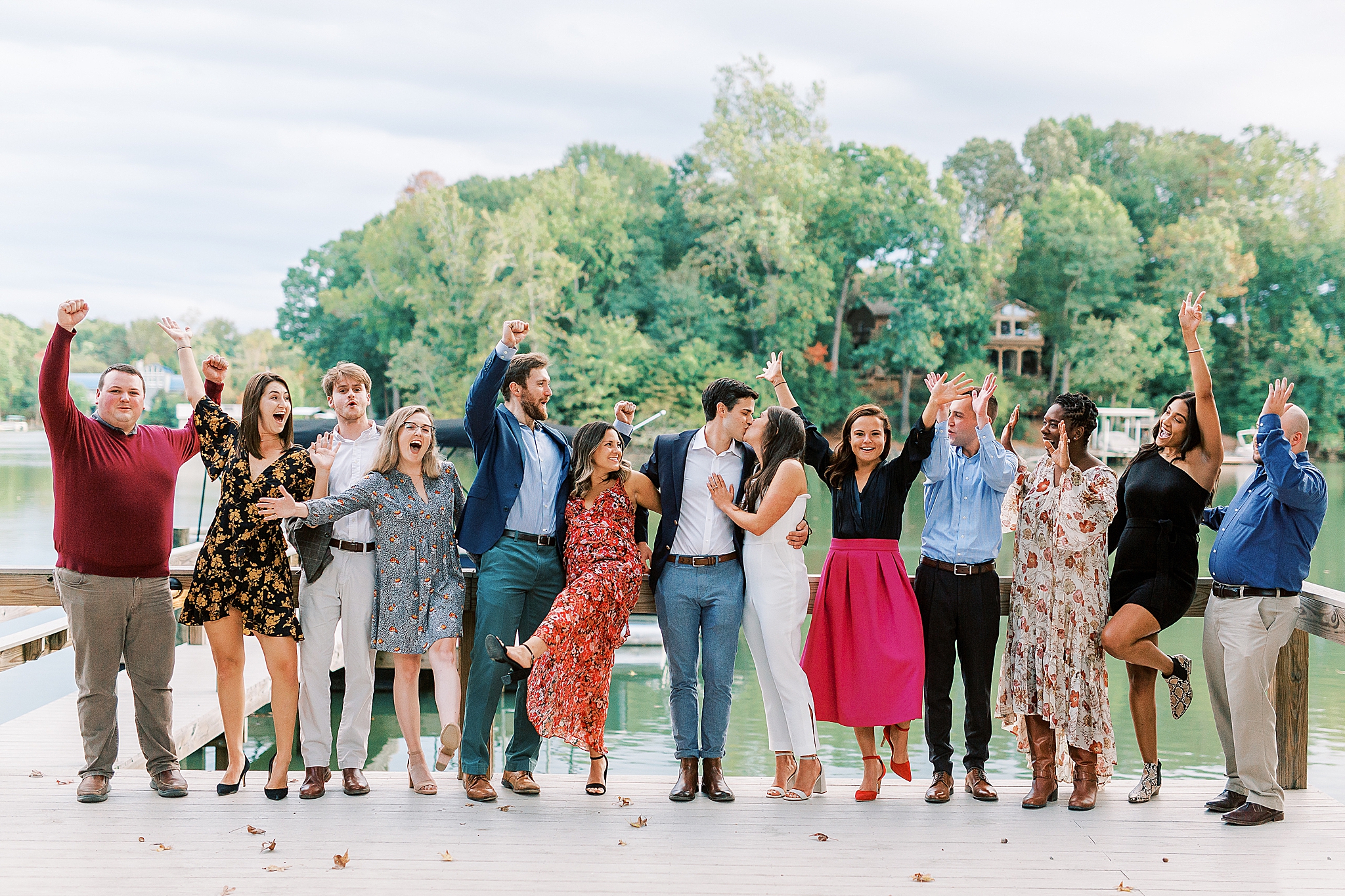 bride and groom pose with wedding party during welcome dinner at Lake Wylie