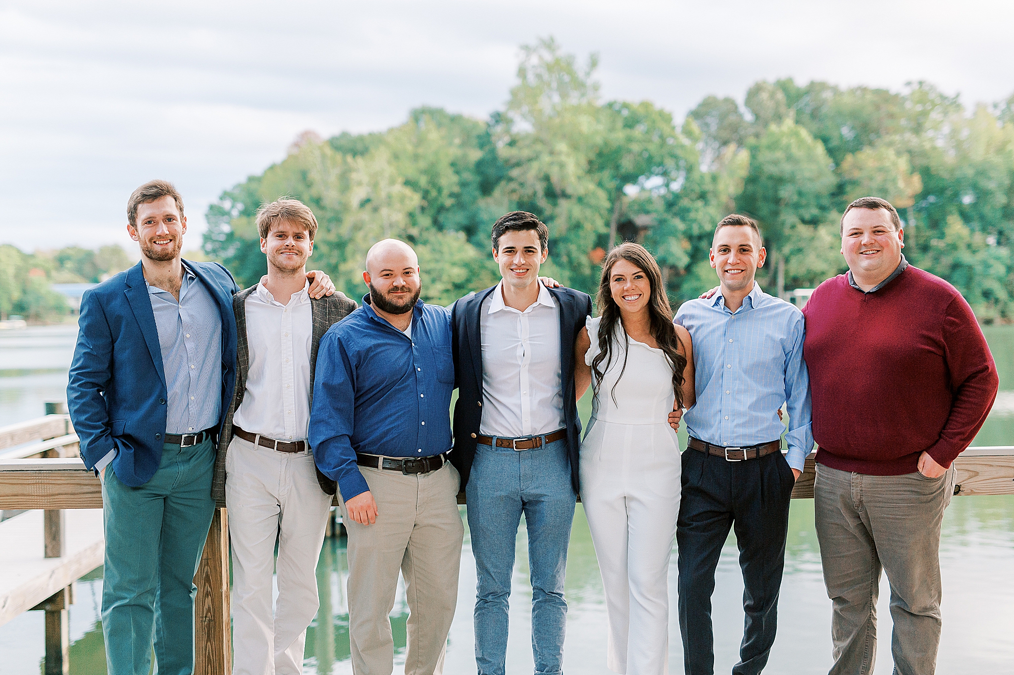 bride and groom pose with wedding party during welcome dinner at Lake Wylie