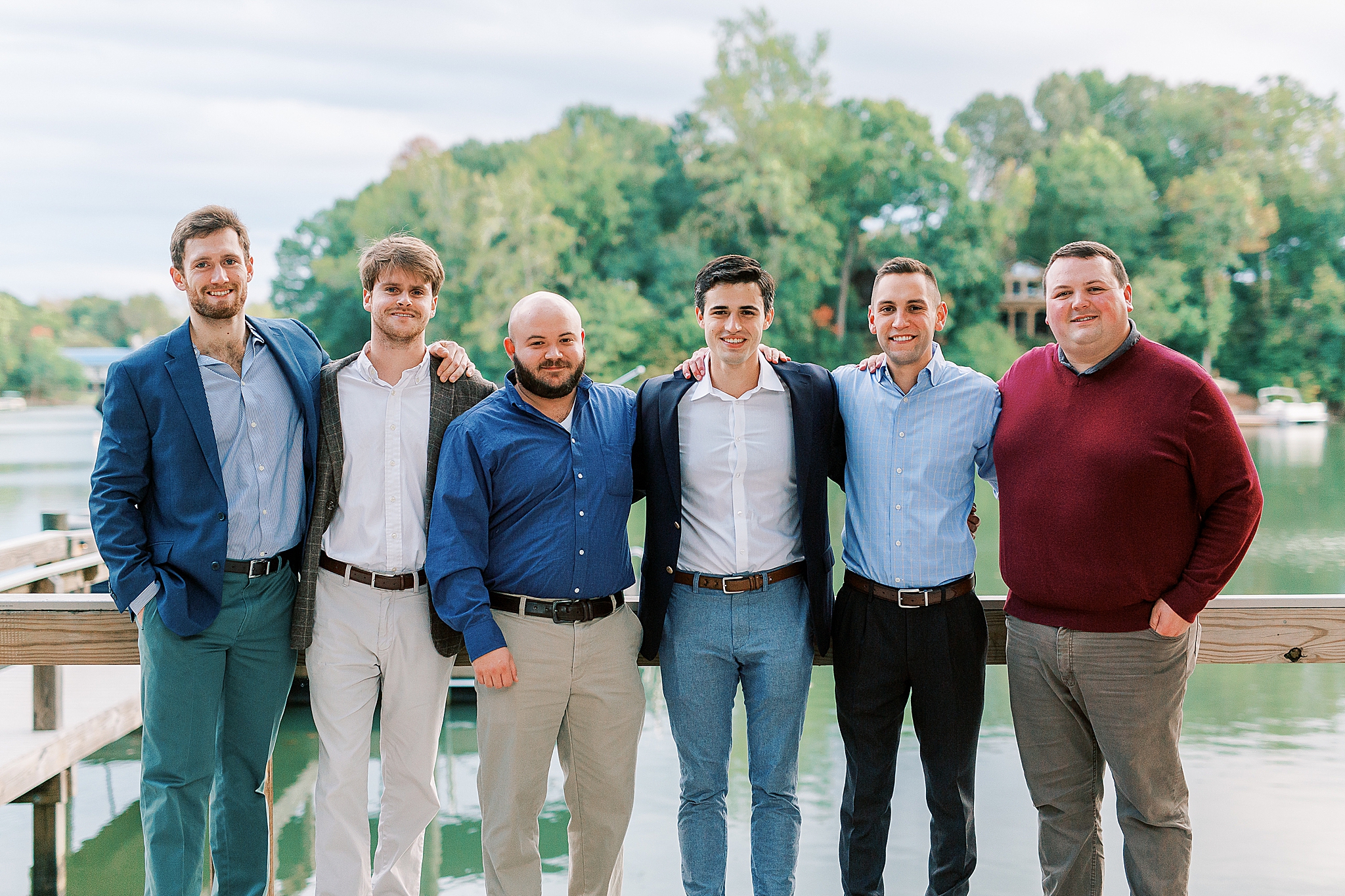 bride and groom pose with wedding party during welcome dinner at Lake Wylie