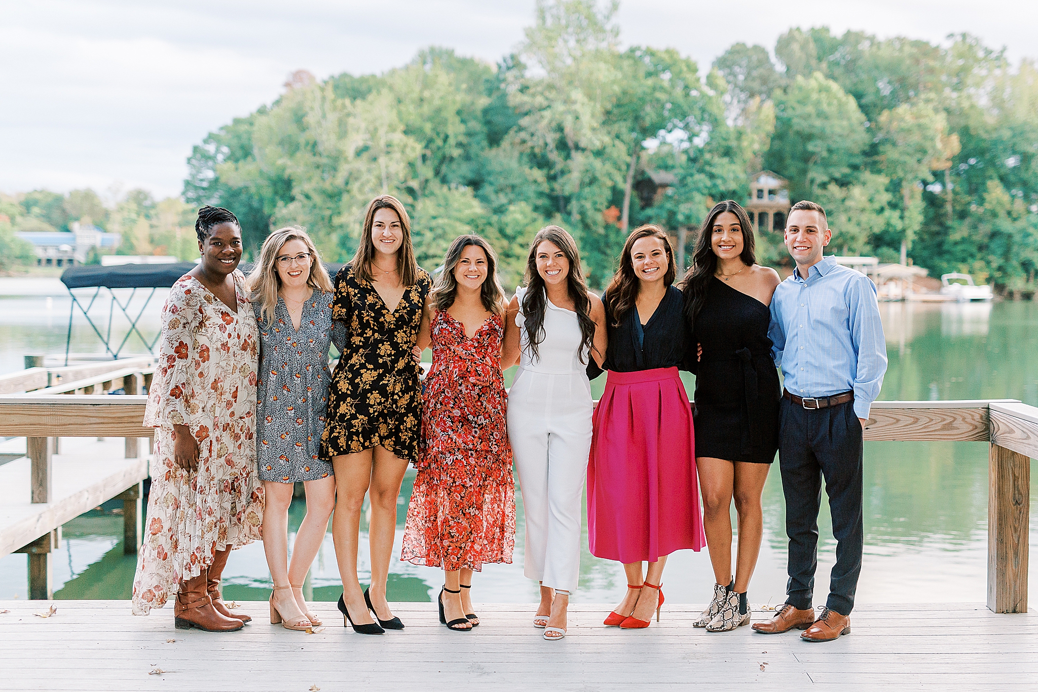 bride and groom pose with wedding party during welcome dinner at Lake Wylie