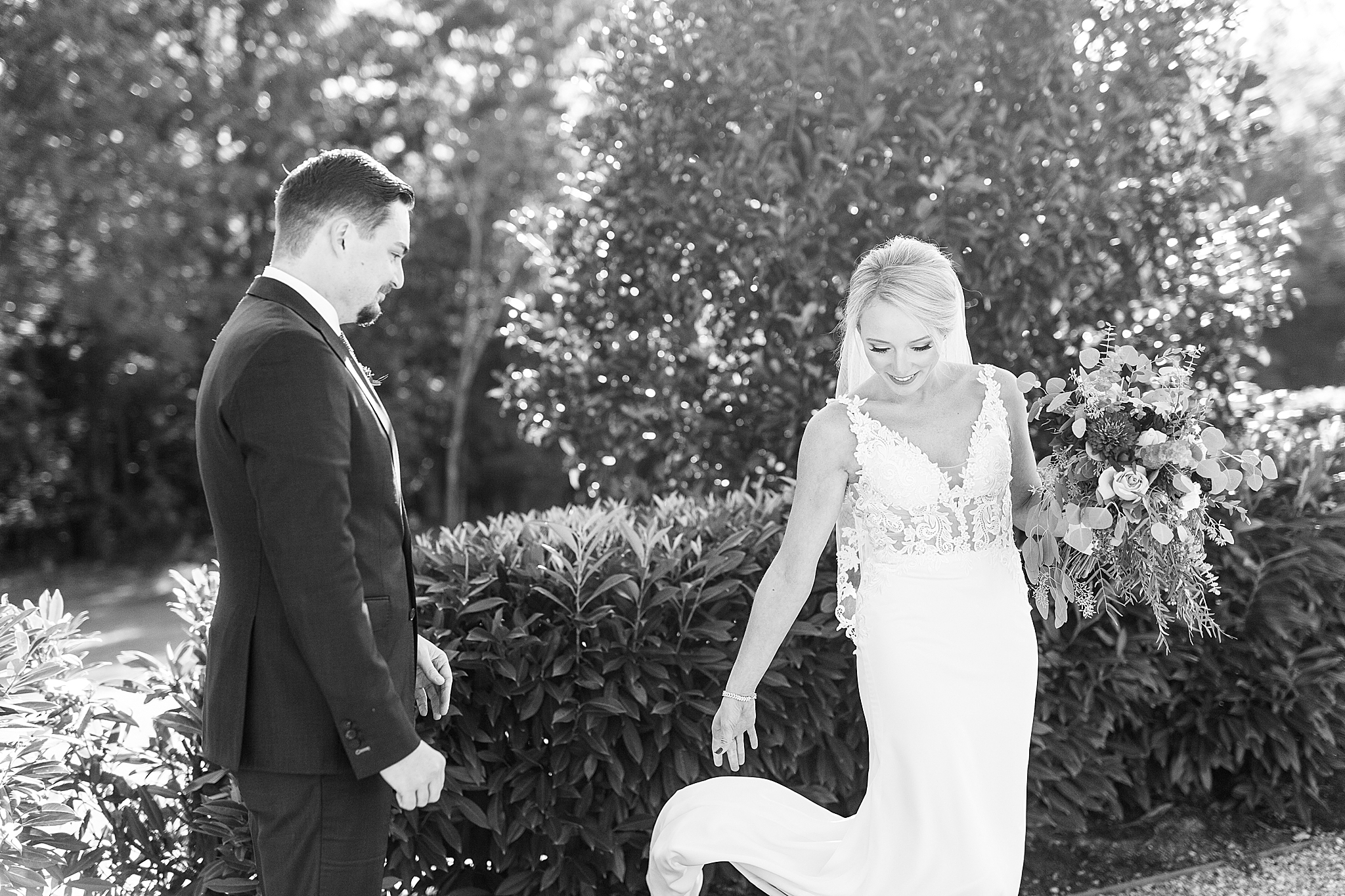 bride shows groom wedding dress during first look