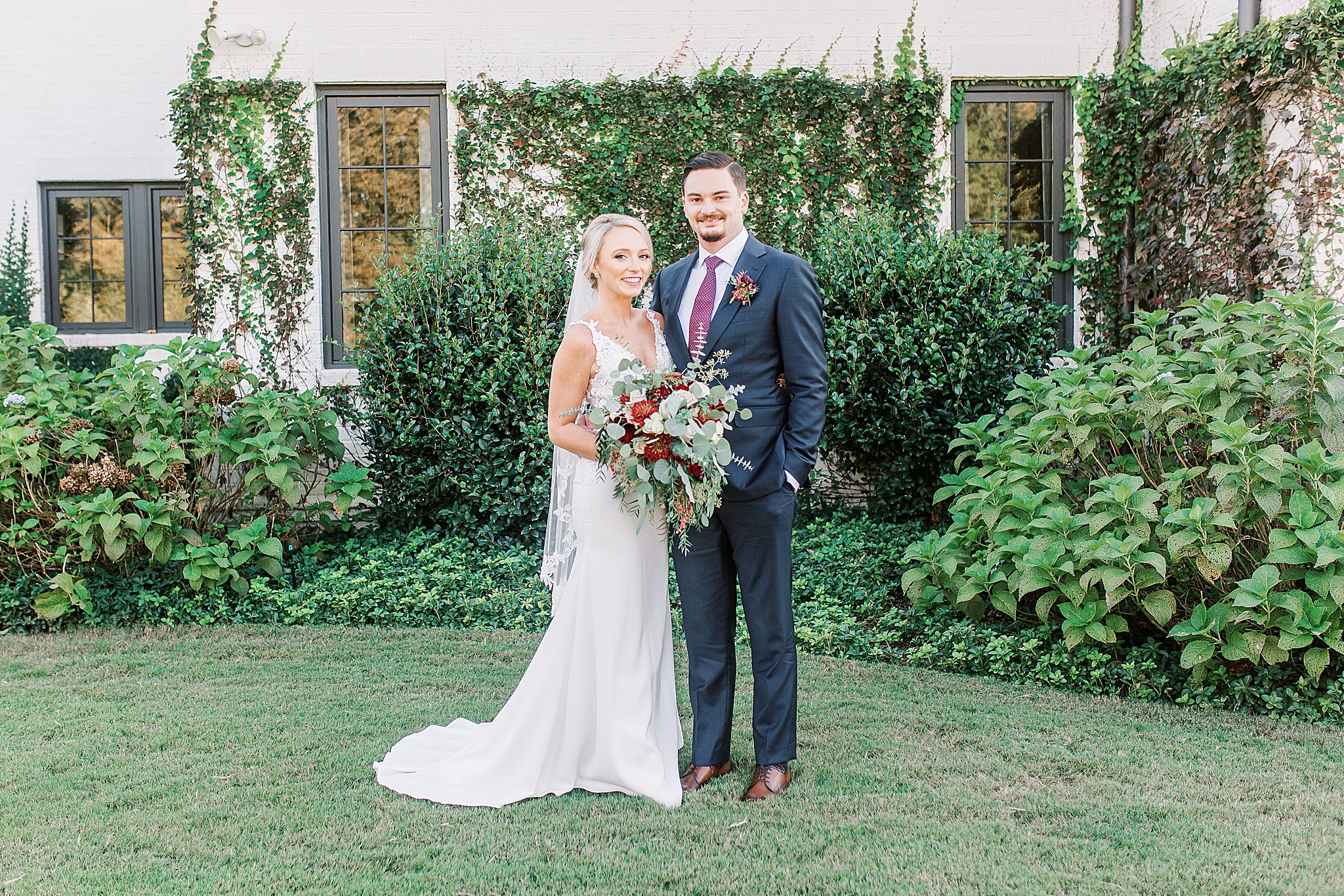newlyweds pose by farmhouse at The Andrews Farm
