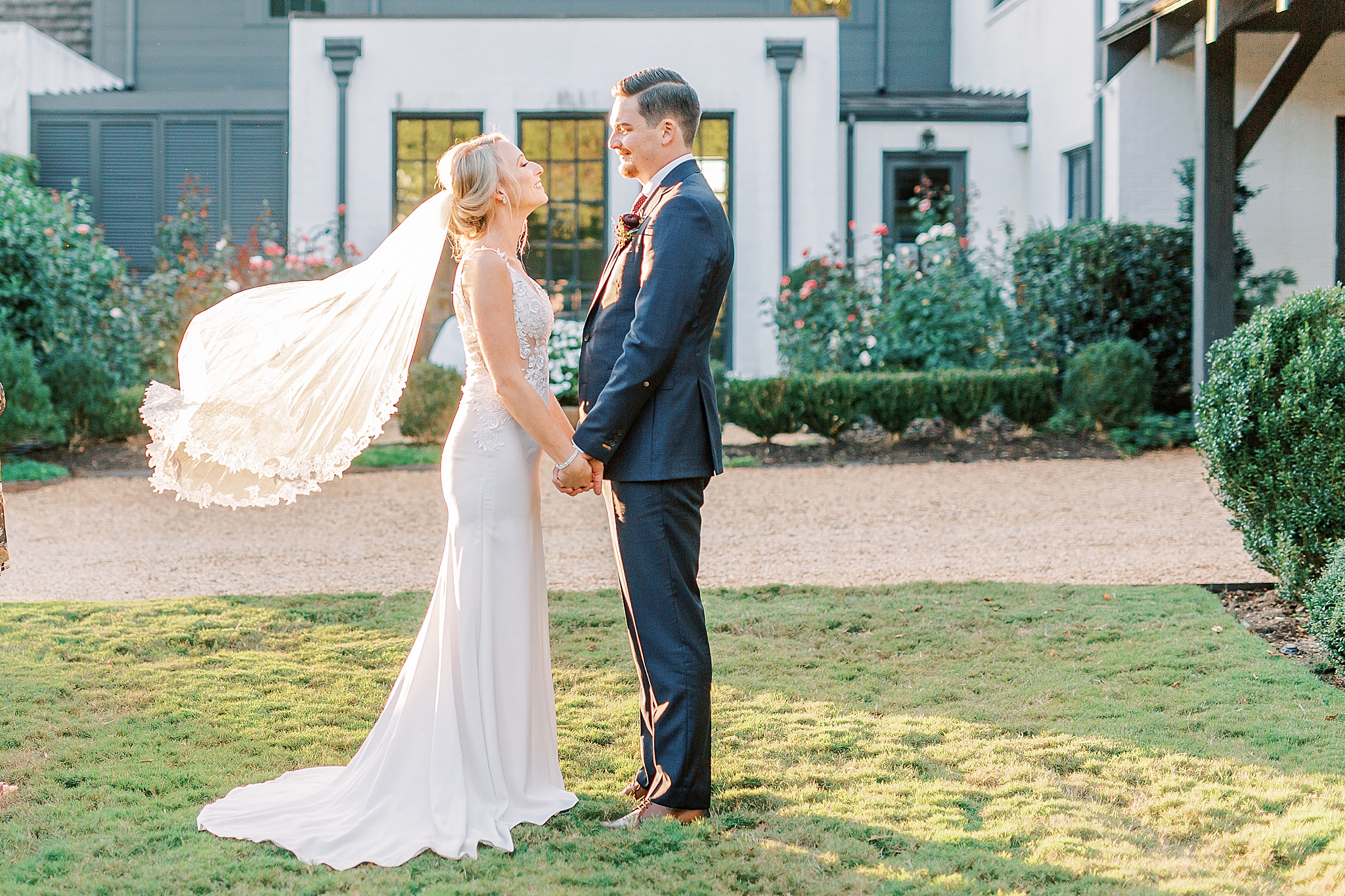 bride and groom hold hands while bride's veil floats in the air