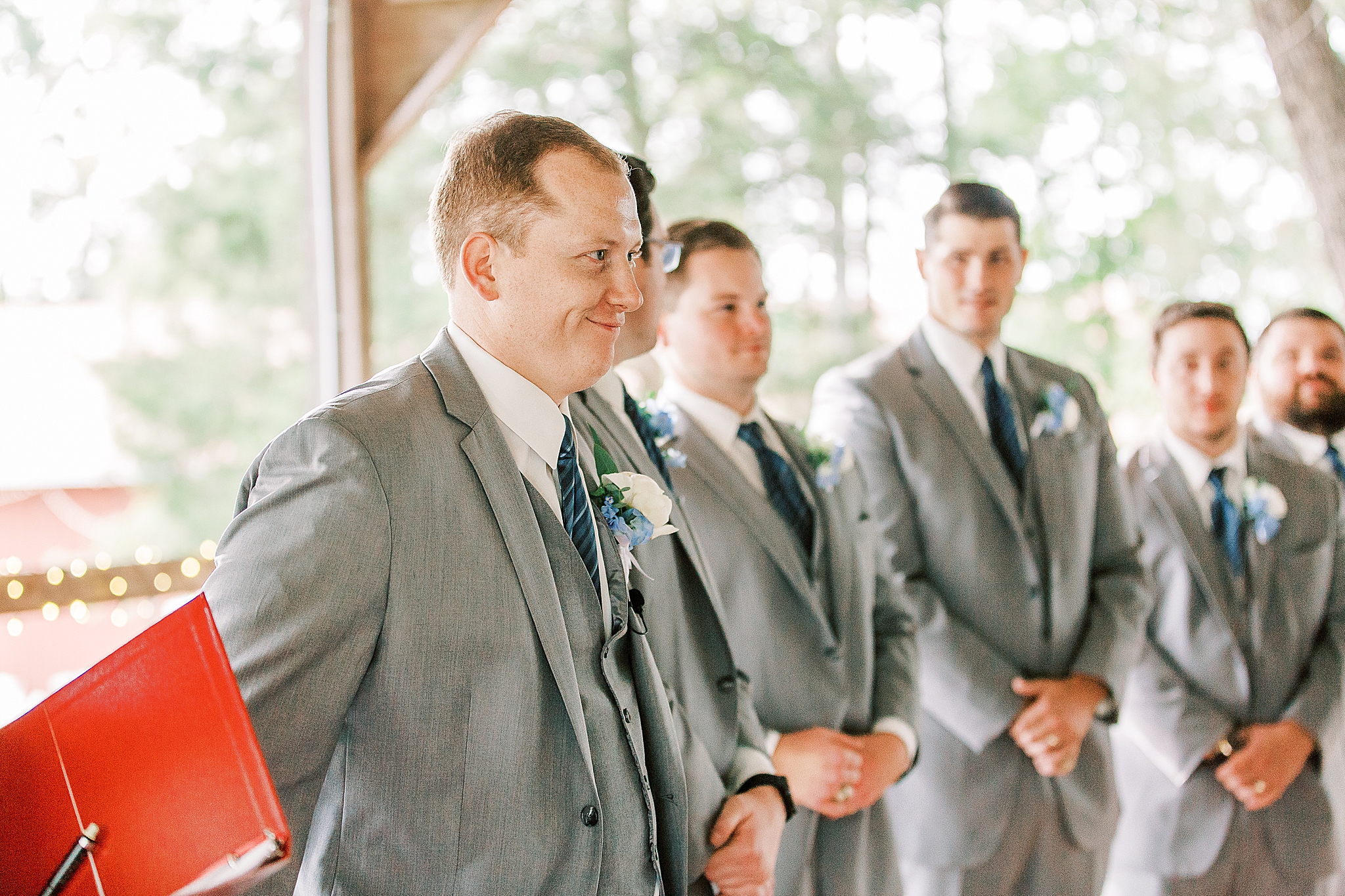 groom smiles watching bride walk down aisle