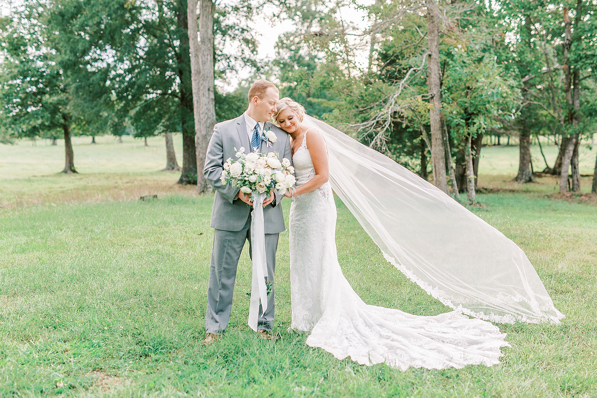 bride leans against groom with veil floating in the air