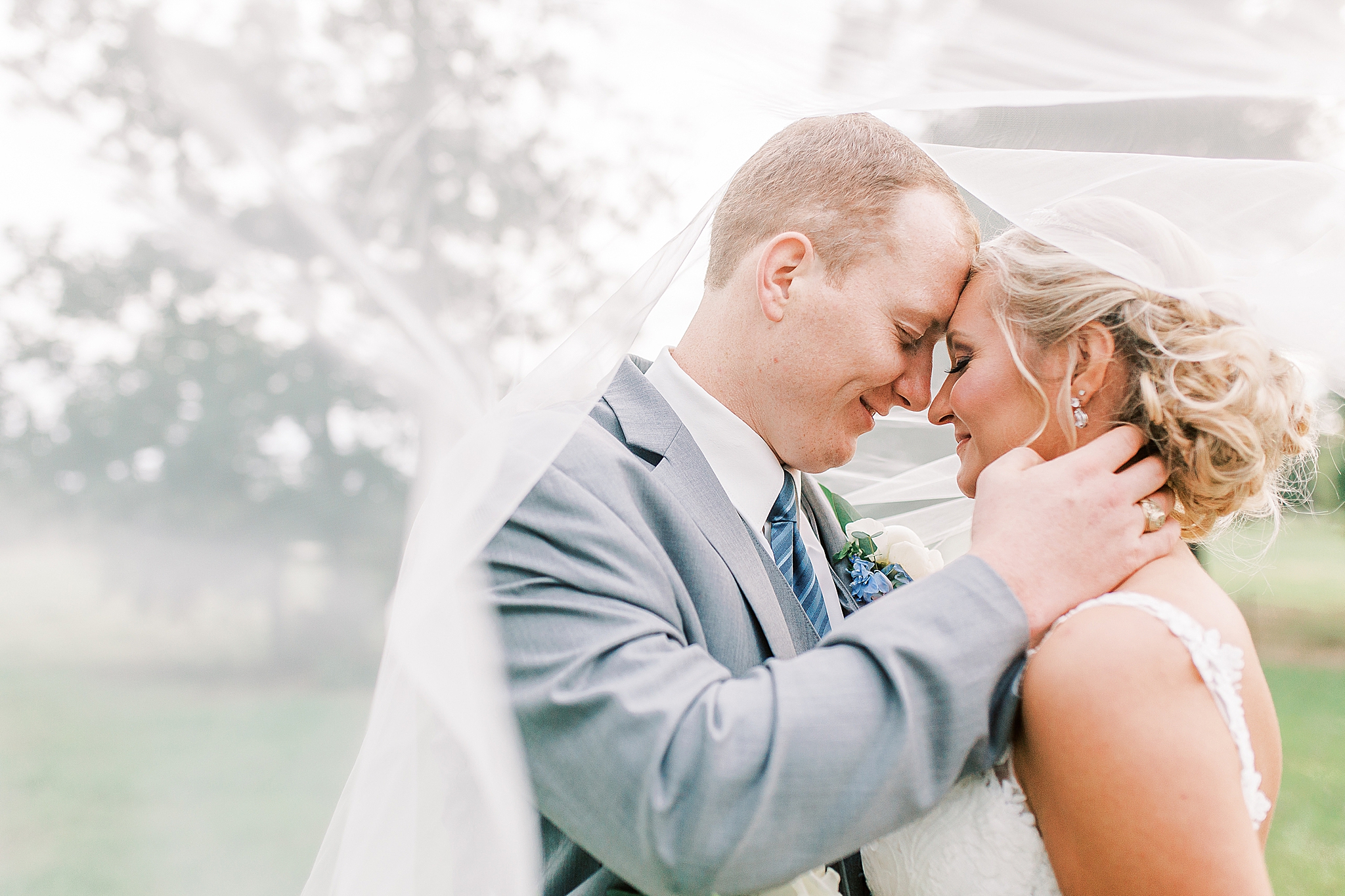bride and groom pose under bride's veil