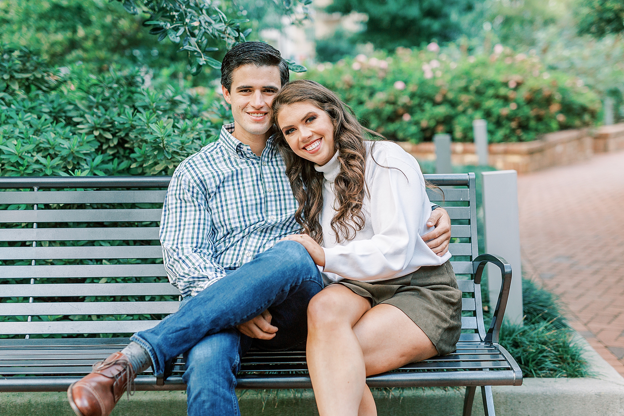 engaged couple sits on park bench in Romare Bearden Park
